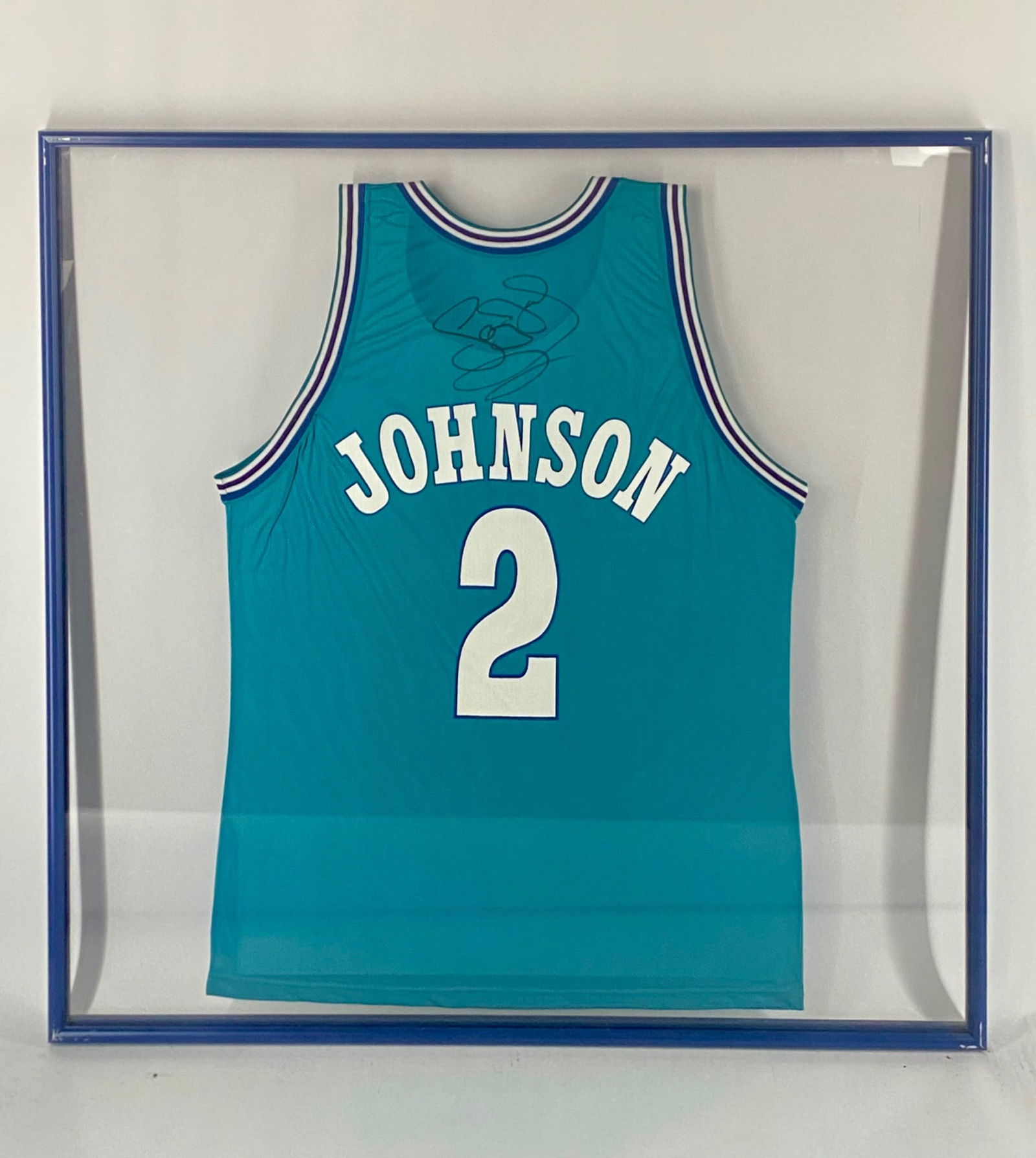 Larry Johnson Signed Charlotte Hornets Champion Framed Jersey: Authentic Champion Charlotte Hornets teal jersey, featuring CHARLOTTE across the front and JOHNSON 2 on the back. The jersey is signed by former NBA All-Star Larry Johnson on the back in black marker.