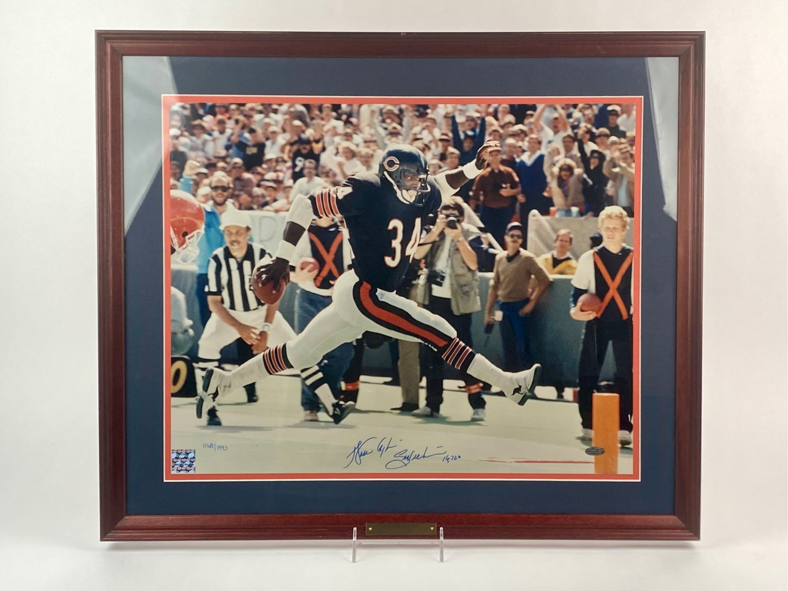 Walter Payton Signed "Step Kick" Framed Photograph Celebrity App: Signed and framed Walter Payton photograph titled "Step Kick." The image captures Payton mid-air in his iconic leaping stride for the Chicago Bears. The photograph is hand-signed in blue ink by Payton