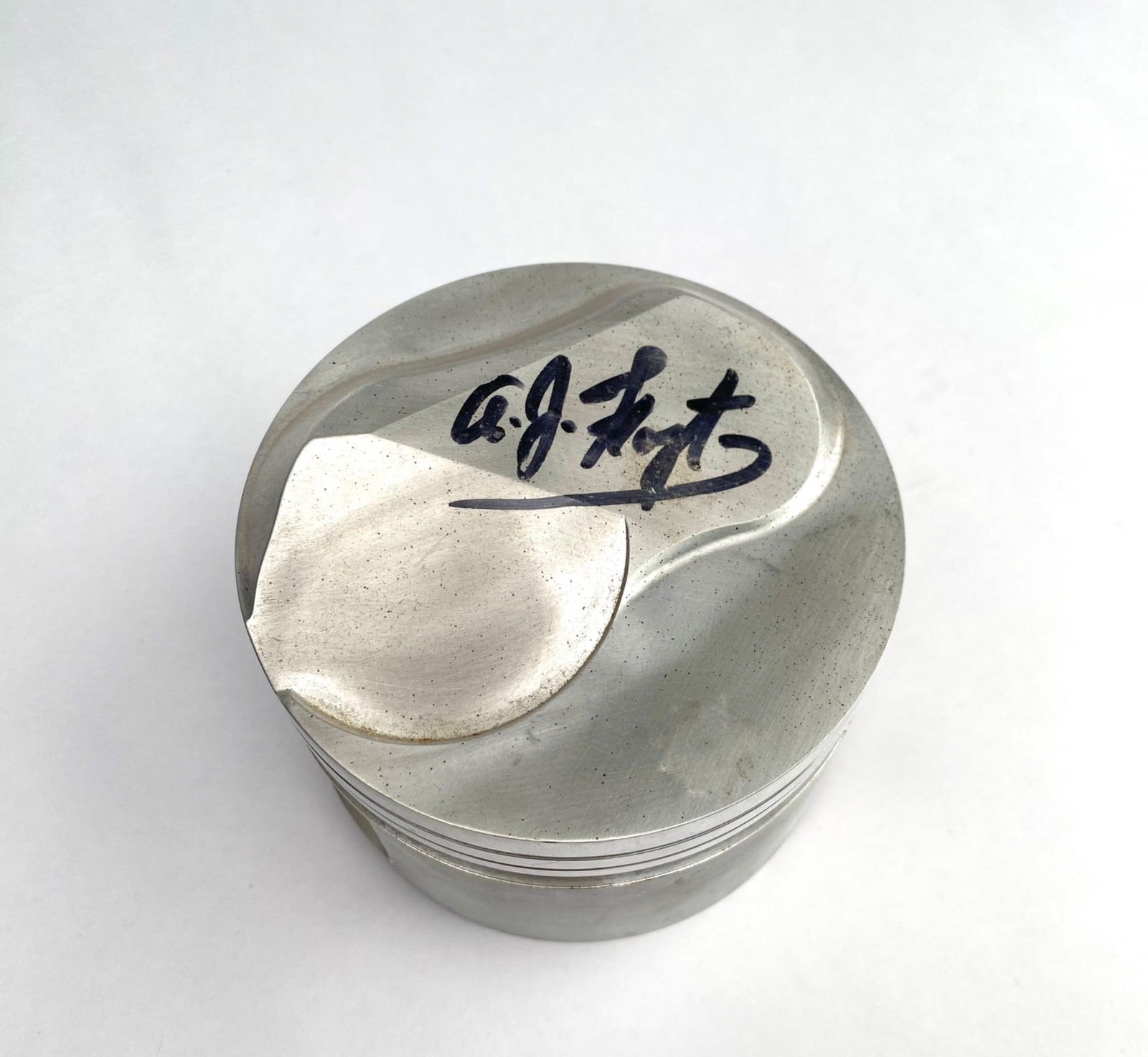 AJ Foyt-Signed Cosworth Racing Piston: Cosworth-engine piston bearing an AJ Foyt signature. Constructed of lightweight metal, with intricate machining and internal details. Markings include "COSWORTH," "R10778/1," and "+.003" on the interi