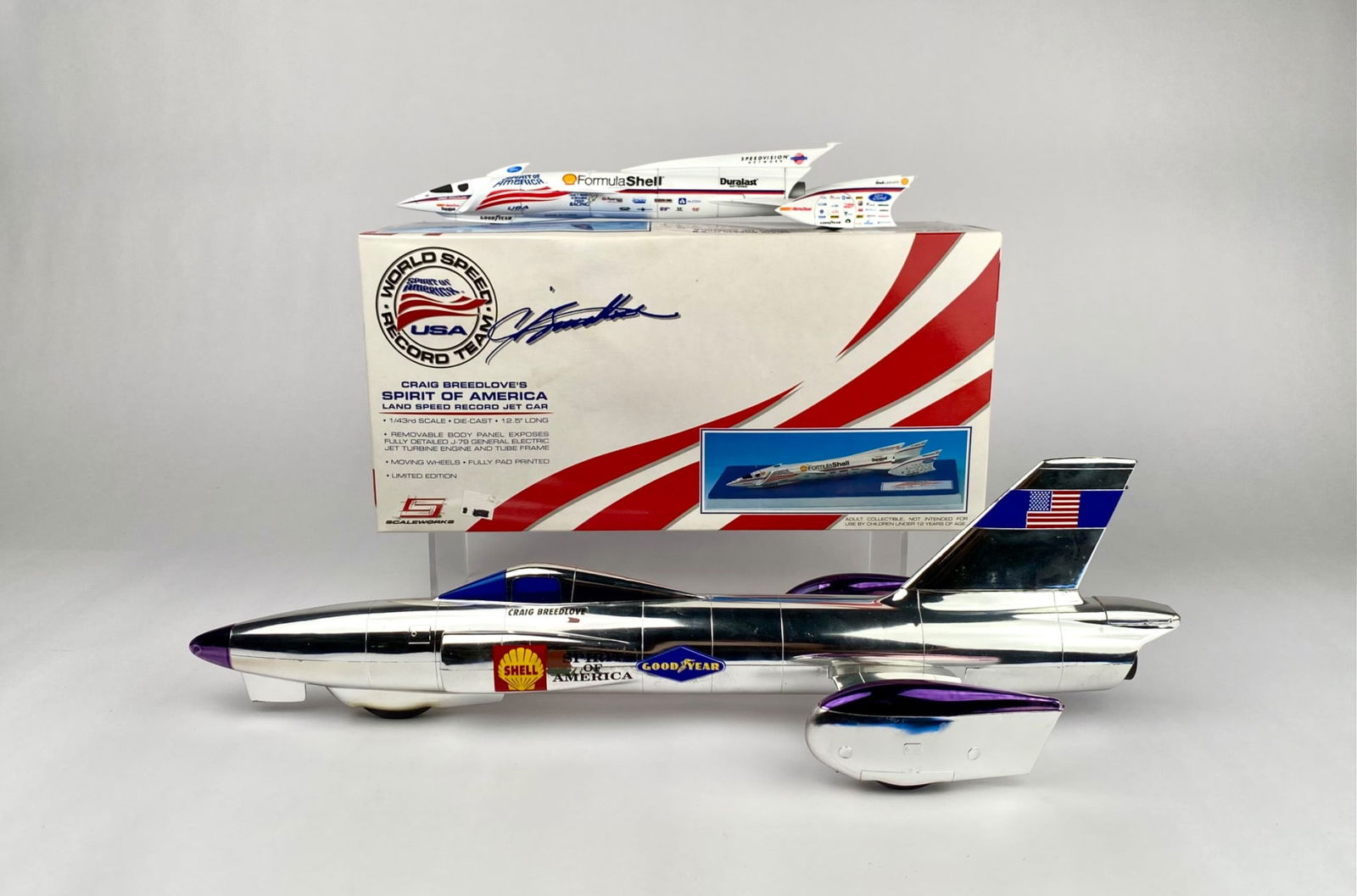 Craig Breedlove Spirit of America Record Jet Car Models with Box: Two models of the Craig Breedlove Spirit of America land speed record jet cars, featuring detailed designs and decals, one in a polished metallic finish and the other in a Formula Shell racing livery.