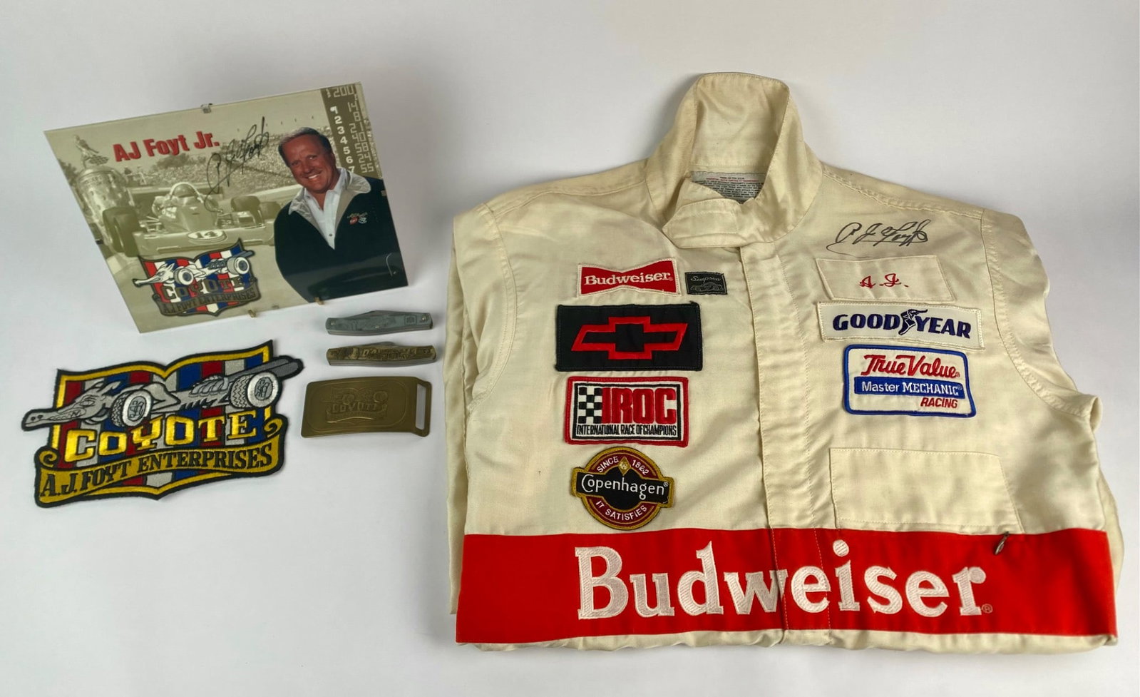 AJ Foyt Jr. Signed Racing Suit with Memorabilia Set: Collection of A.J. Foyt racing memorabilia highlighted by a Simpson racing suit featuring Budweiser, Chevrolet, Goodyear, Copenhagen, and IROC patches. The suit is autographed by A.J. Foyt on the ches