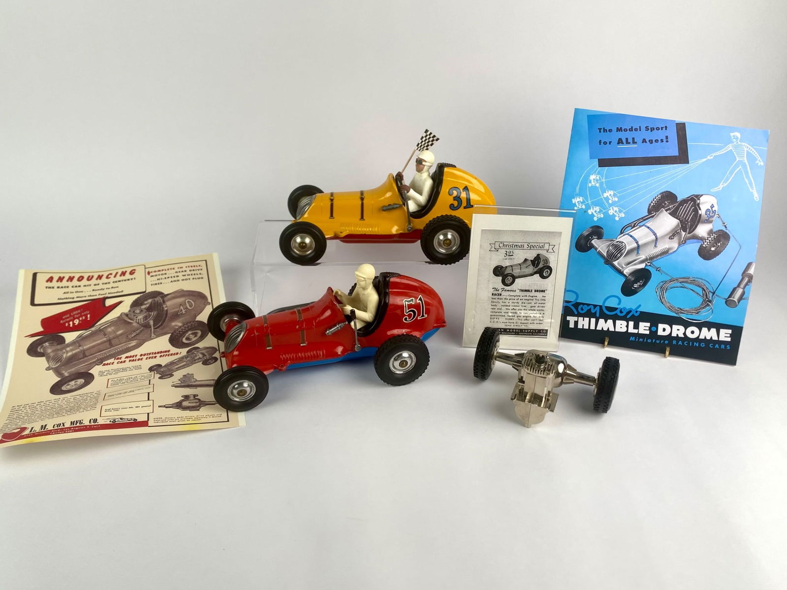 Set of Cox Thimble-Drome Champion Tether Cars with Ephemera: Set of vintage Cox Thimble-Drome Champion tether cars and related ephemera. The lot includes two Champion races, one red car numbered 51, and one yellow car numbed 31, each with molded driver figures
