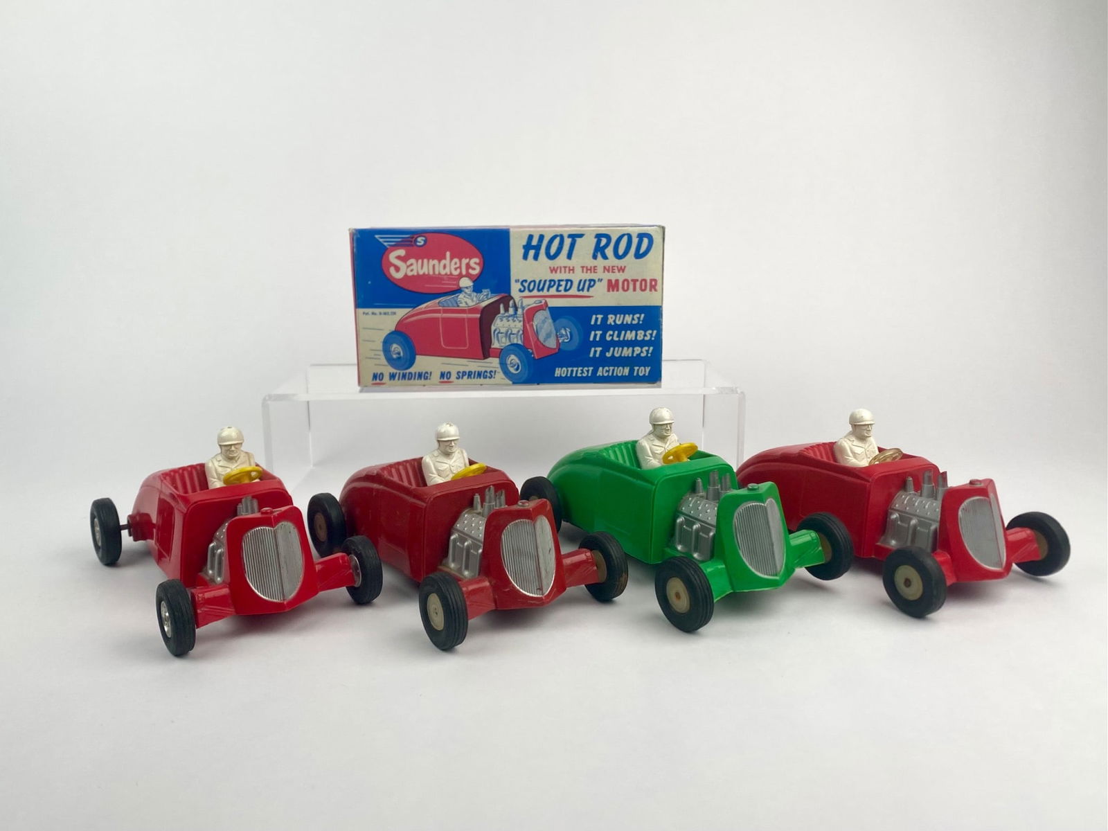 Lot of Four Saunders "Souped Up" Hot Rod Cars with Original Box, 1950: Set of four vintage Saunders "Souped Up" Hot Rod friction cars, manufactured by Saunders Tool & Die, Aurora, Illinois, circa 1950. Each car features a molded plastic body in red or green with a driver