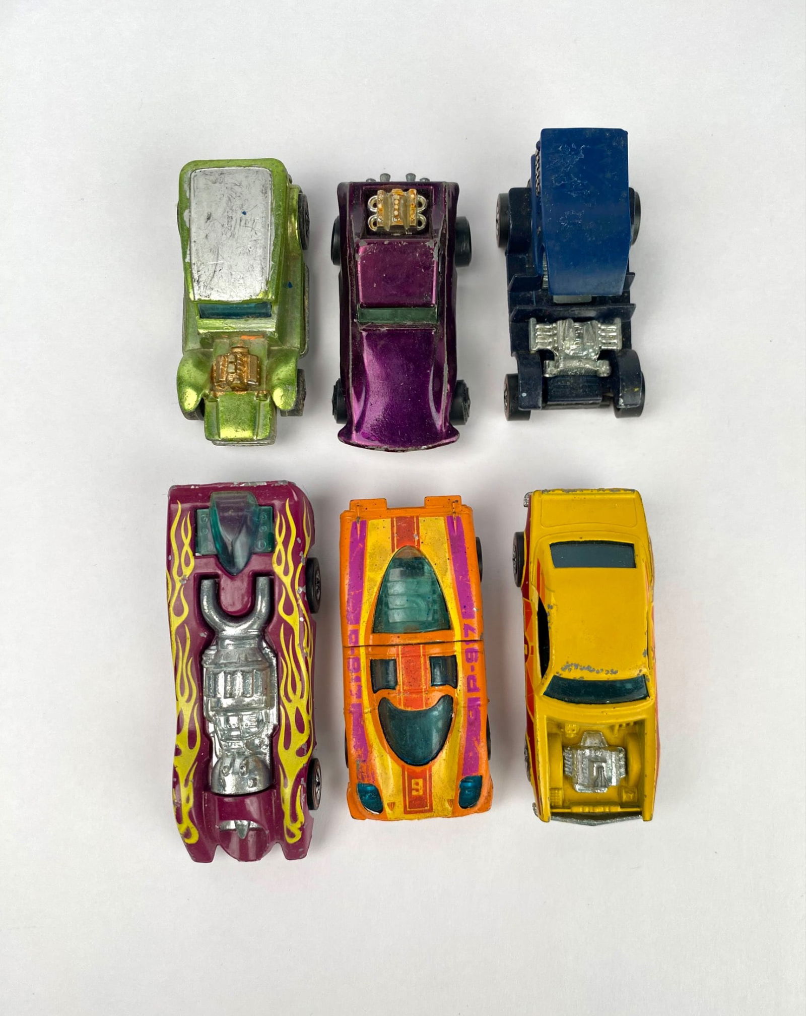 Lot of 6 Vintage Hot Wheels Redline and 1970s Models: Six vintage Hot Wheels die-cast cars, featuring various designs, paint schemes, and styles. Some vehicles display unique details, including decals, flames, and distinctive body shapes. Made of metal a
