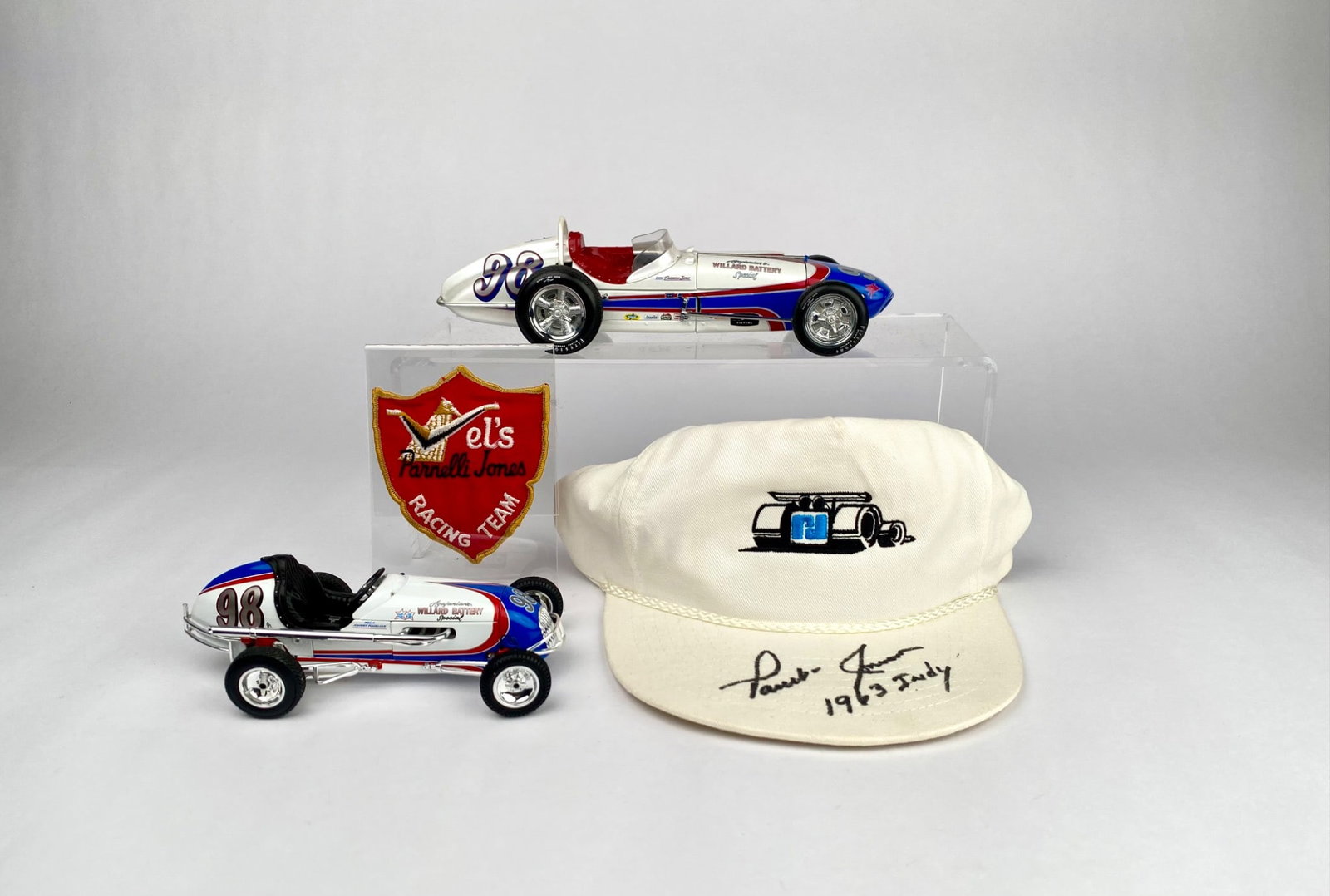 Parnelli Jones Signed Cap with Racing Team Patch and Two Die-Cast Race Car Models with boxes and COA: A signed white cap embroidered with a race car illustration and Parnelli Jones autograph dated 1963 Indy. Includes a Mel's Parnelli Jones Racing Team patch displayed in a clear case. Also features two