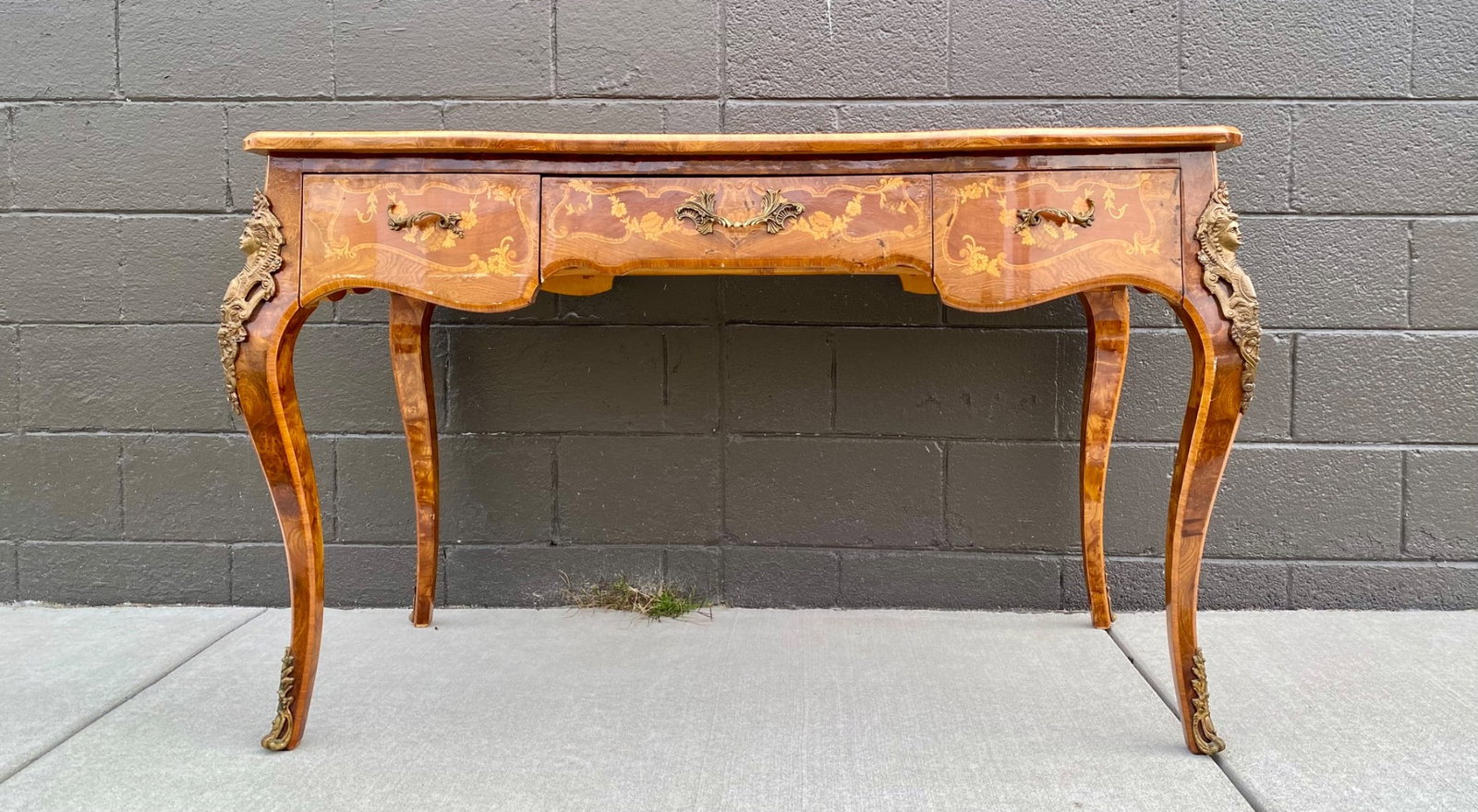 Louis VX Style Inlaid Writing Desk with Ormolu Mounts: Louis VX style wooden writing desk featuring intricate marquetry inlay with floral motifs. The desk has a contoured leather-inset top and ormolu mounts, including ornate female busts and botanical det