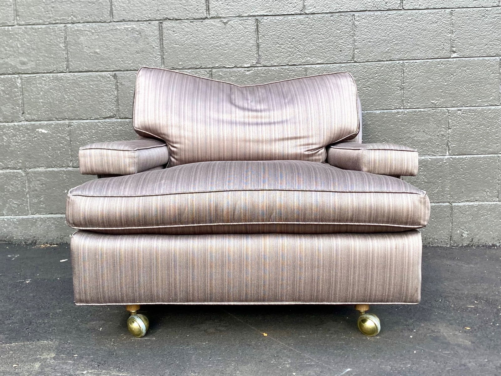 Mid-Century Modern Oversized Club Chair on Brass Ball Casters: Mid-century modern upholstered club chair featuring a deep cushioned seat, loose back pillow, and wide track arms. The chair is covered in a striped fabric with subtle iridescent undertones. It rests