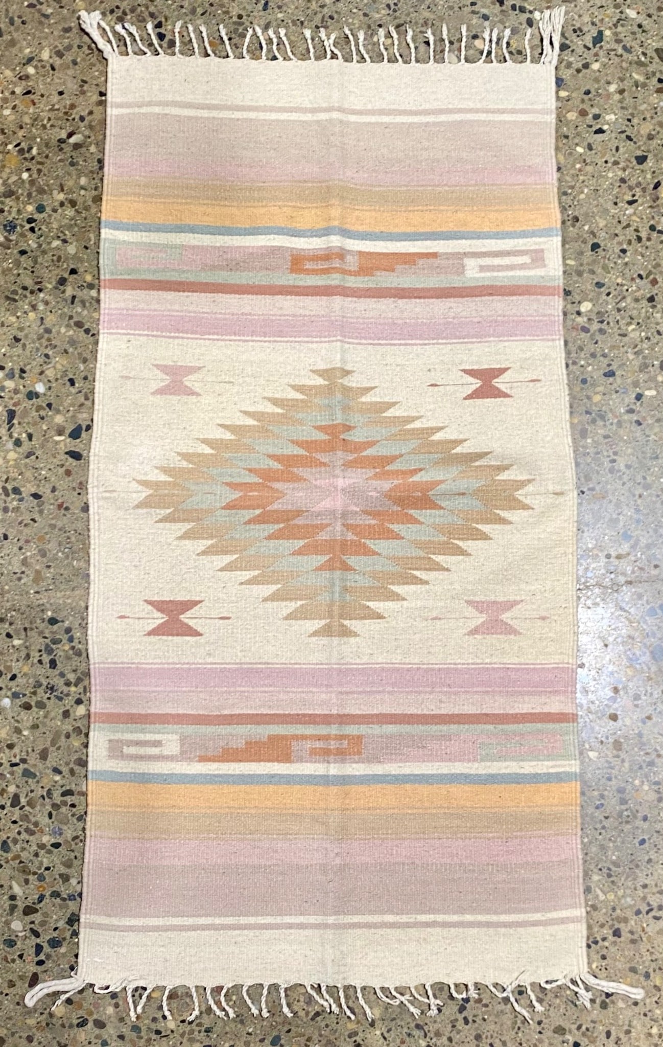 Pastel Southwestern Diamond Motif Wool Rug: Pastel Southwestern rug featuring a geometric diamond design in pastel colors, including beige, pink, orange, and blue. The central diamond motif is complemented by smaller geometric elements. Fringed