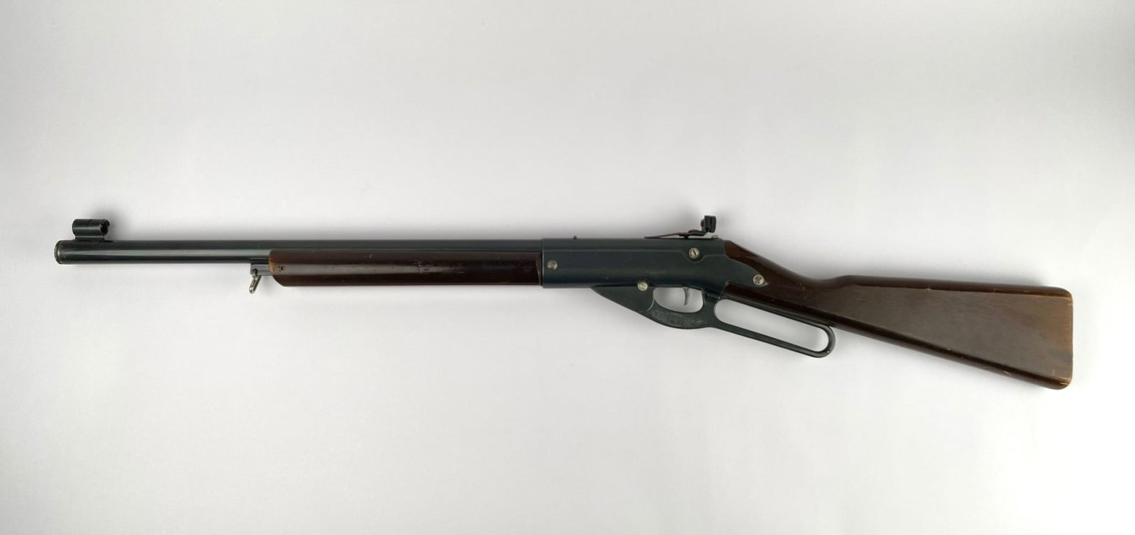 Daisy Model 99 BB Gun Lever Action Air Rifle: Daisy Model 99 BB gun lever action air rifle with wood stock and forearm, and metal barrel and frame. Markings on the barrel include the model number and manufacturer information, identifying it as pr