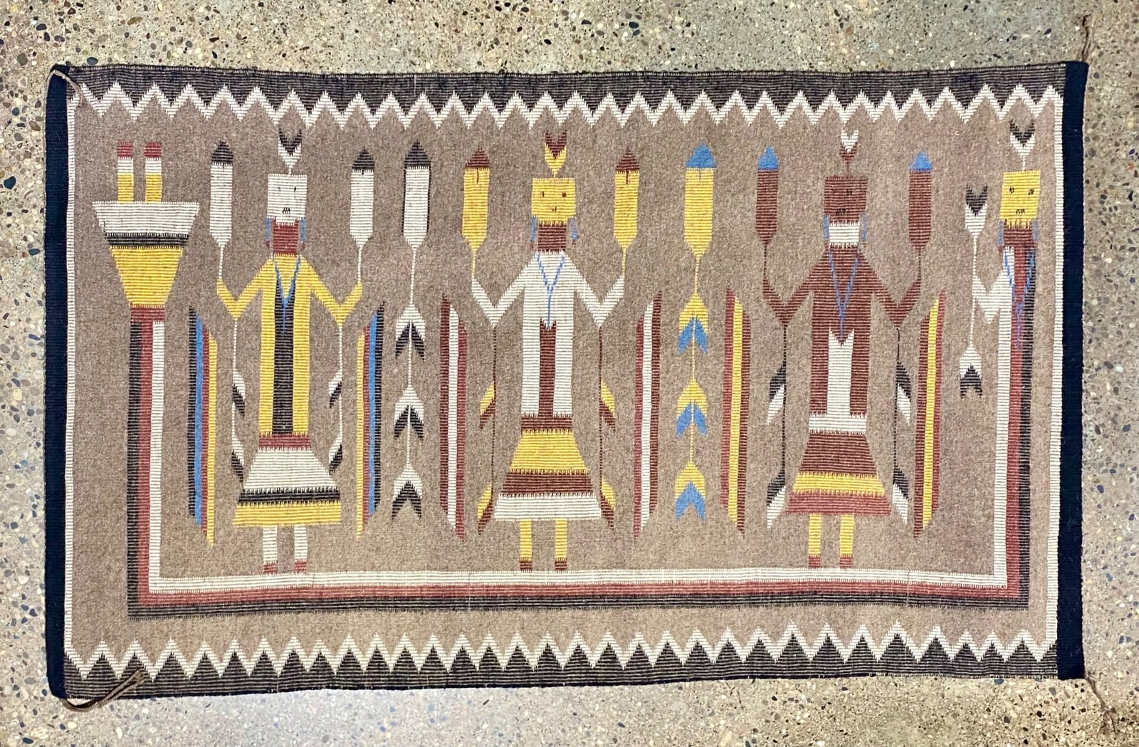 Handwoven Navajo Yei Rug with Geometric Patterns and Figures: Handwoven Navajo Yei rug featuring a detailed design of geometric patterns and Yei figures in a palette of tan, brown, yellow, white, blue, and black. Includes a border with traditional stepped patter