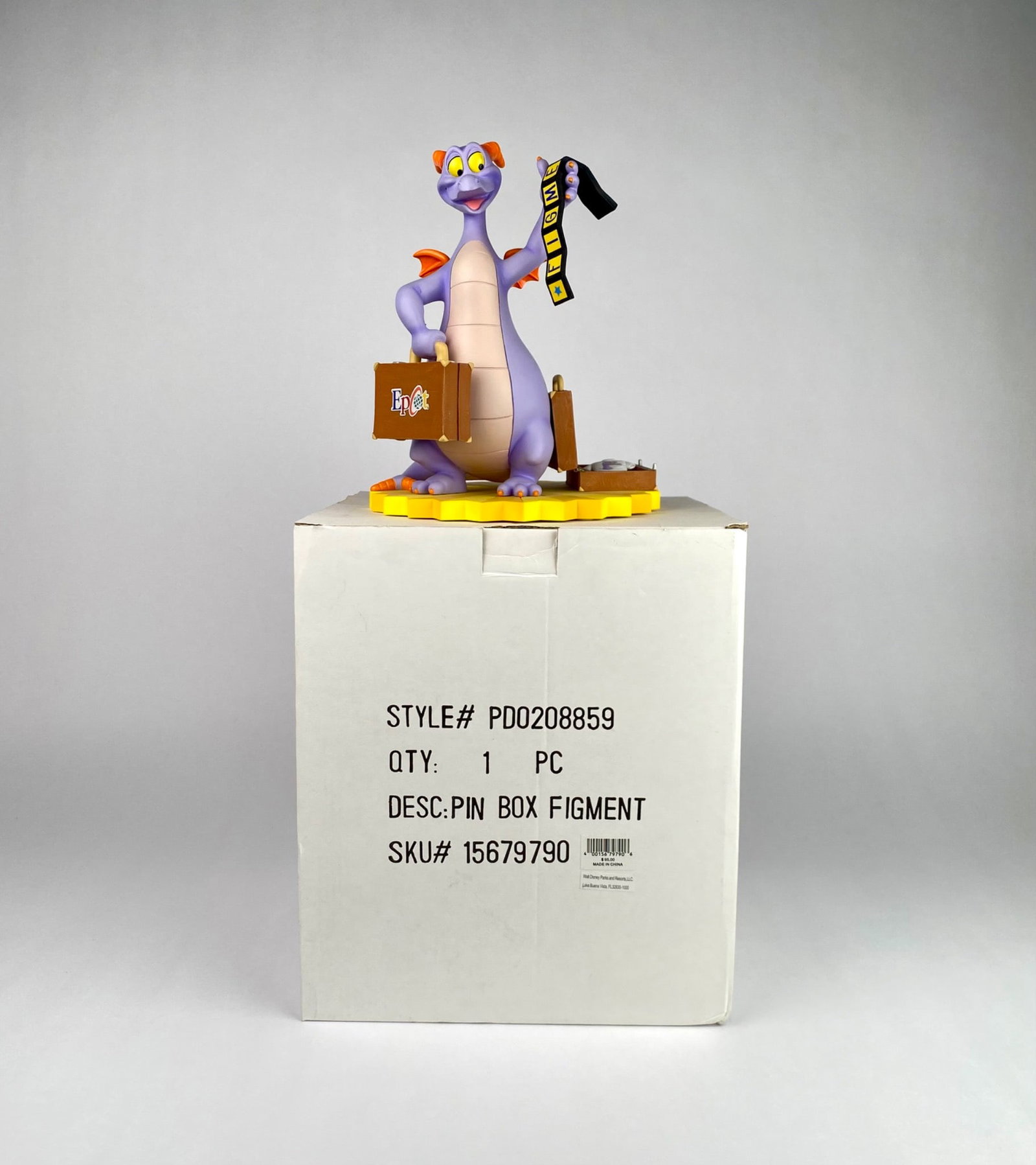Disney Parks EPCOT Figment 'Pin Box' Figurine with Pin: Disney Figment figurine featuring the beloved character holding suitcases and a banner. Comes with a shirt pin bearing the Figment character design and an Epcot logo suitcase. Base features Disney bra