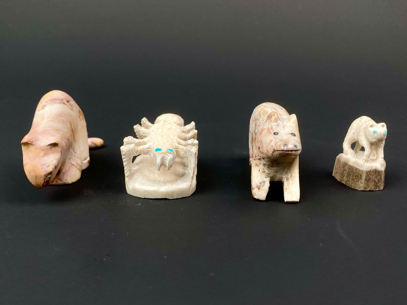Group of Four Carved Zuni Animal Fetishes (Mountain Lion, Spider, Bear & Cougar): Lot includes four carved Zuni animal fetishes; each made from bone or antler with inlaid eyes. The mountain lion is signed on the underside and carved from warm tone antler or fossil material with nat