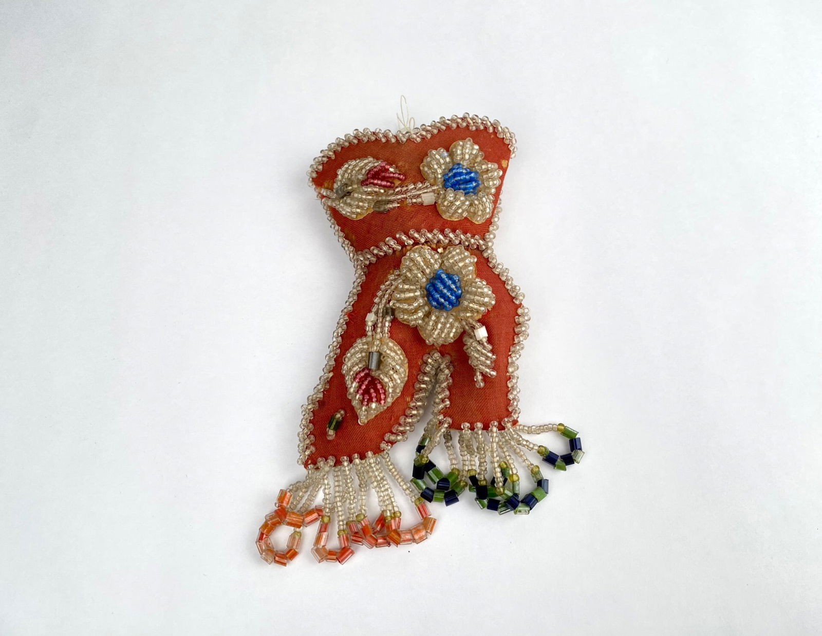 Iroquois Beaded Whimsy Pin Cushion, Floral Motif: Beaded Haudenosaunee (Iroquois) pin cushion featuring an intricate design of flowers and leaves made with colorful seed and tubular beads. The item incorporates a red fabric base, embroidered and ador