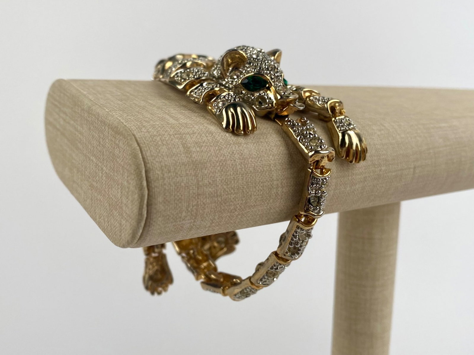 Articulated Crystale-Pave Panther Gold Tone Bracelet: Articulated panther-form bracelet featuring a fully sculpted feline design with hinged segments that allow it to curve around the wrist. The bracelet is set with clear pave rhinestones throughout and 