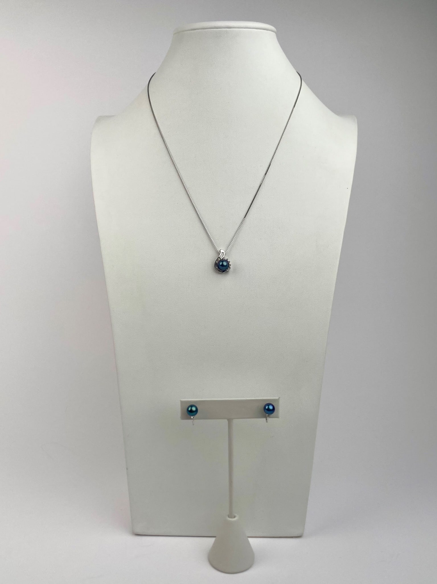 14K White Gold Blue Pearl & Diamond Pendant Necklace and Earrings Set: | 14K white gold jewelry set featuring a blue pearl and diamond pendant necklace paired with matching earrings. Necklace pendant features a blue pearl set in a swirl accented by tapered baguette-cut d