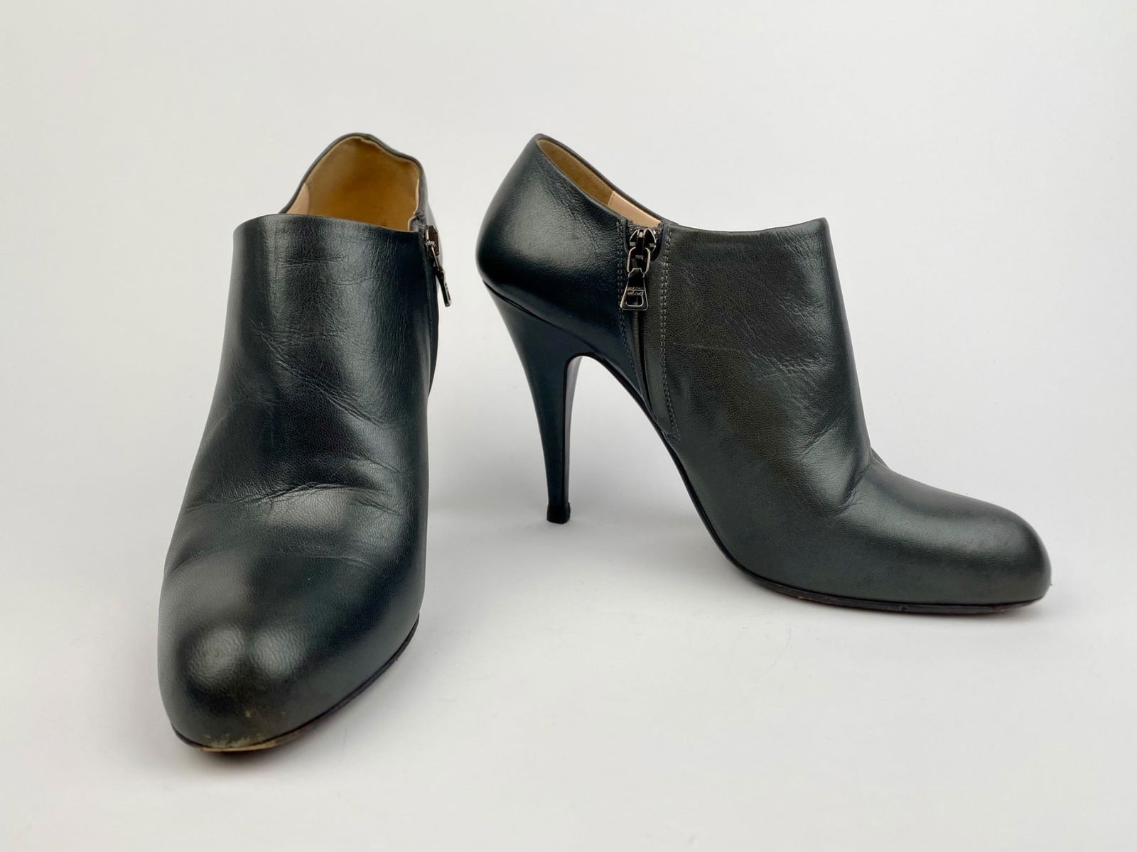 Prada Black Leather High-Heel Ankle Booties, Size 40: Pair of Prada black leather high-heel ankle booties in size 40. The booties feature black leather, rounded toes, and interior side zippered stamped "PRADA MILANO." The soles are marked "PRADA Made in