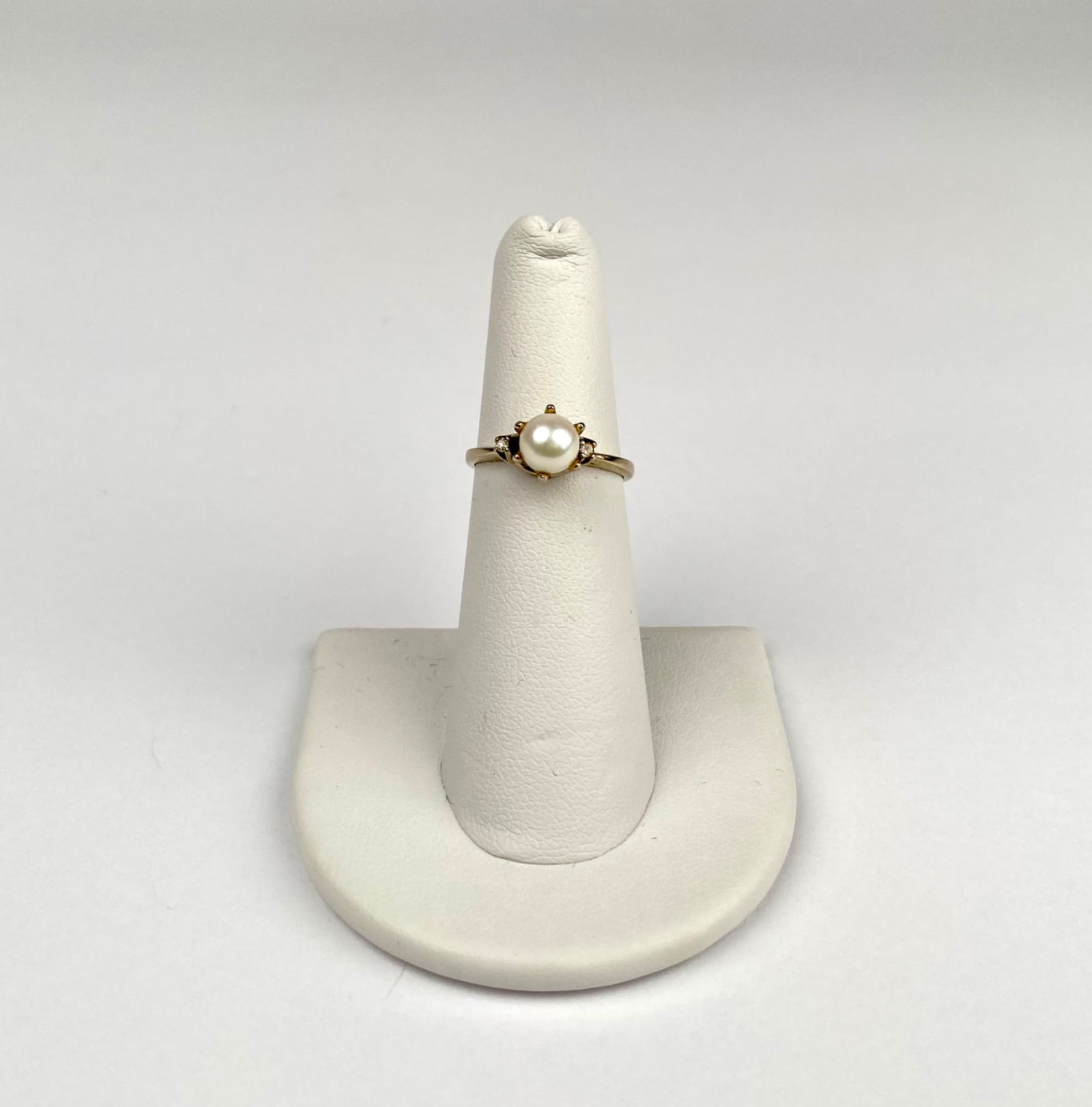 14K White Gold Ring with Pearl & Diamonds: 14K white gold pearl ring with a round cultured white pearl at the center, flanked by four diamond accents. The ring is marked ’14K’ on the band, verifying the gold’s purity. The ring is in good