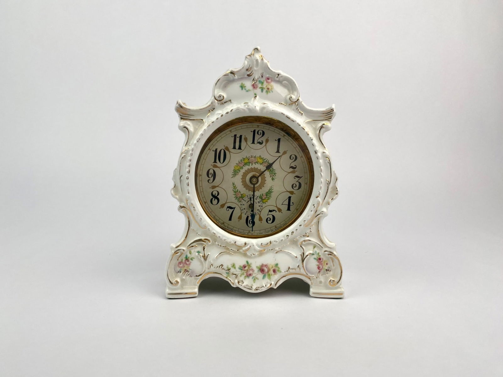 Early 20th Century Wm. L. Gilbert Porcelain Mantel Clock: Early 20th century porcelain mantel clock by the Wm. L. Gilbert Clock Company of Winsted, Connecticut. The ornate white case features Rococo-style scrolling and hand-painted floral decoration with gil