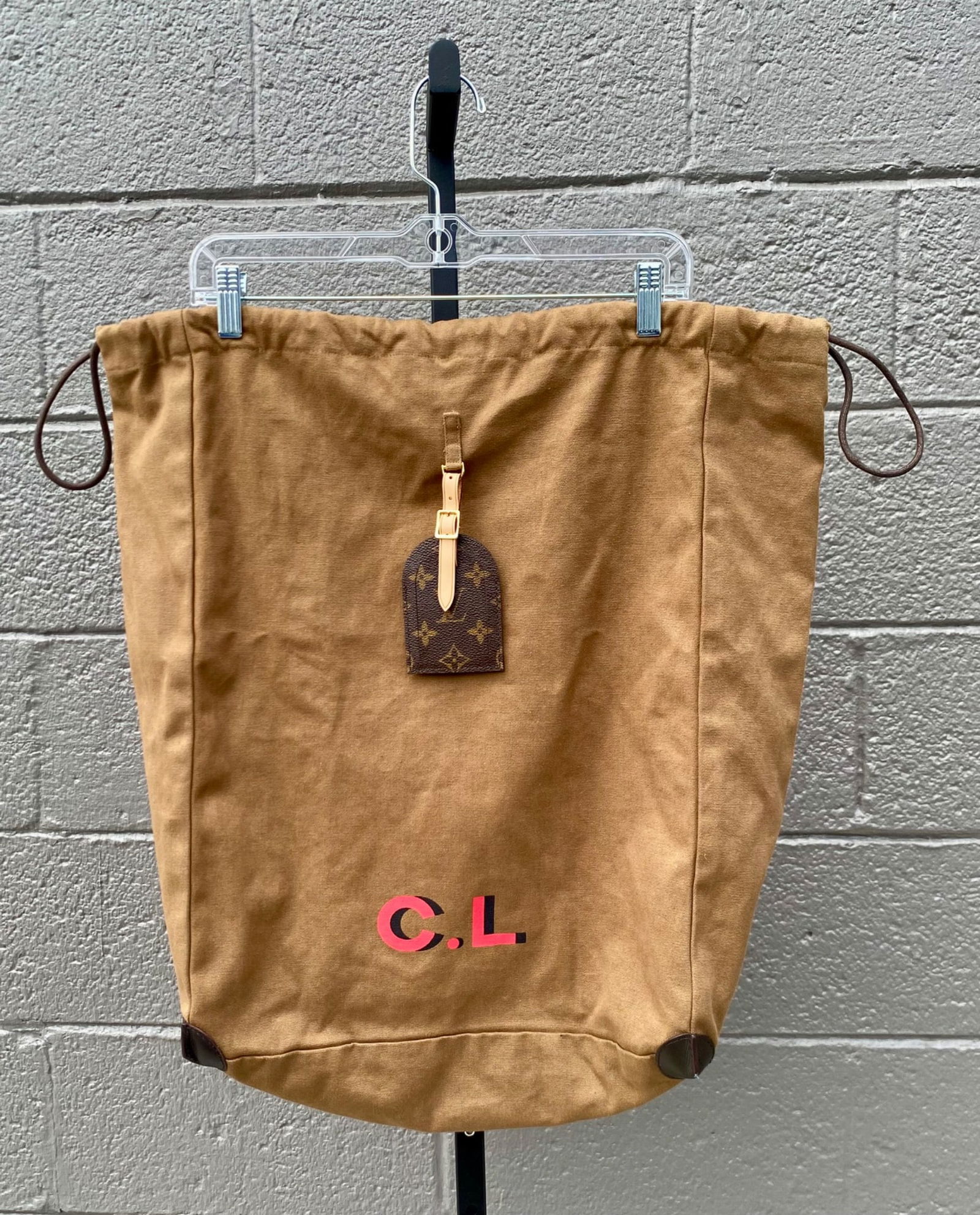 Louis Vuitton Monogram Canvas and Cotton Drawstring Bag: Louis Vuitton drawstring bag made of 99% cotton and 1% leather, featuring monogram canvas accents and stitched initials C.L. in pink and black. Interior is lined in black fabric. Includes a Louis Vuit