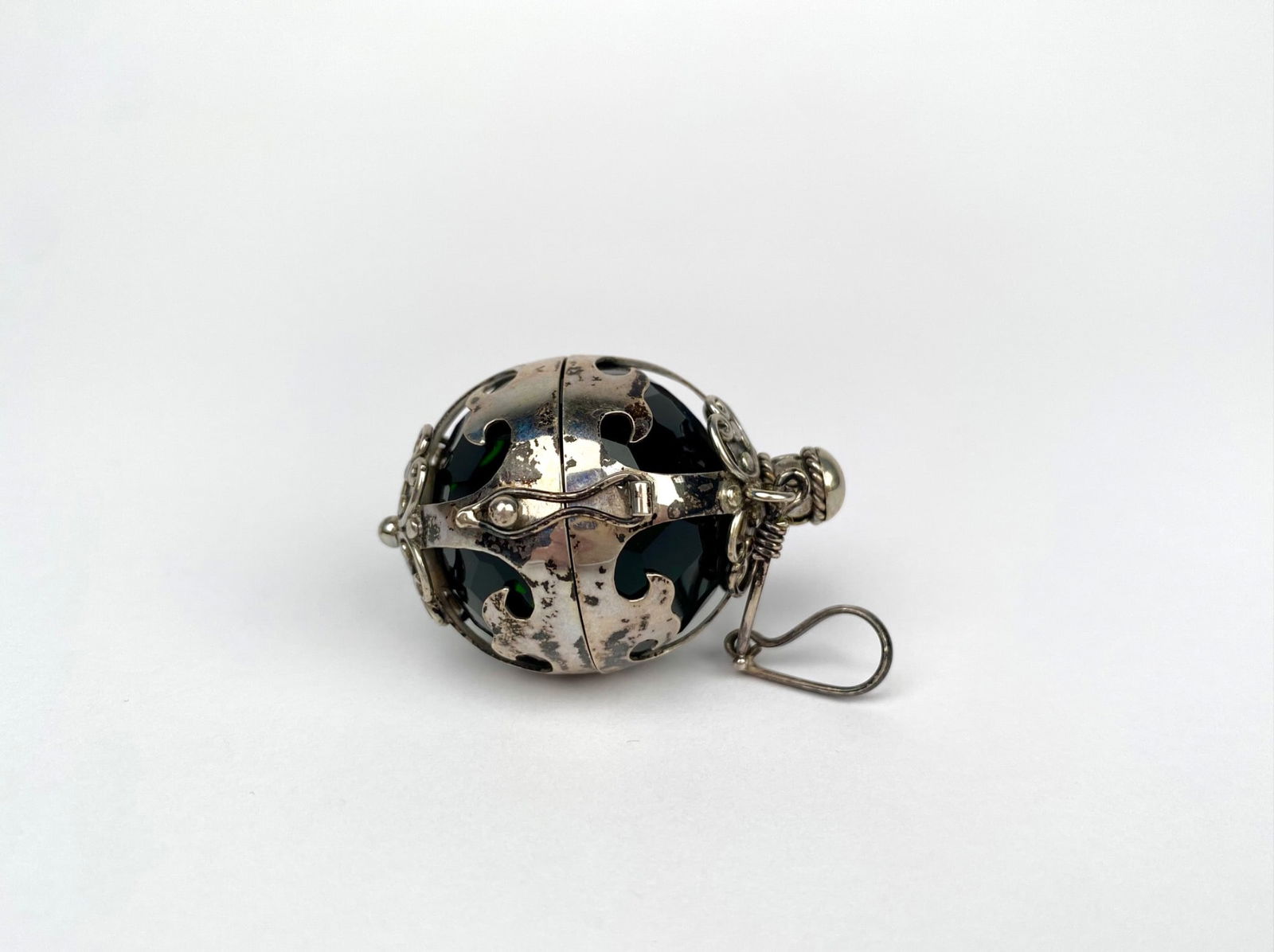 Vintage Sterling Silver Filigree Orb Locket Pendant with Faceted Green Glass: Sterling silver pendant with an intricate filigree design. The piece features a hinged spherical structure that encloses a removable green faceted glass sphere. The silver is marked with "925" indicat