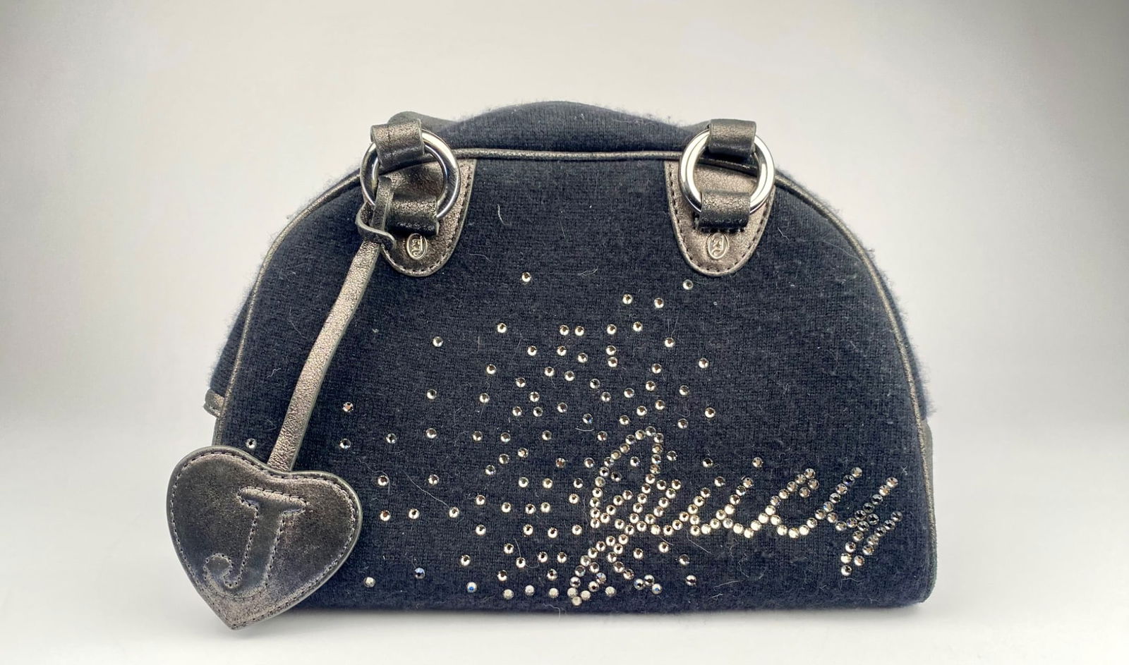Juicy Couture Black Dome Handbag with Rhinestone Accents: Juicy Couture dome-style handbag featuring black wool-like fabric with metallic silver accents and rhinestone embellishments. The word “Juicy” is spelled out in rhinestones on the front, and t