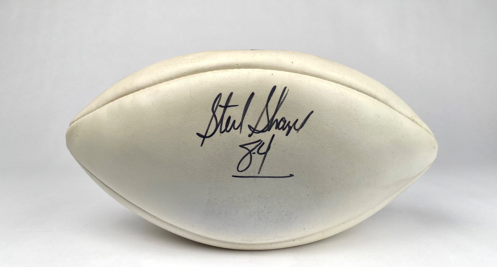 Wilson NFL Football Signed by Sterling Sharpe with Number 84: Wilson official NFL football signed by Sterling Sharpe with “84” below his signature. Features the Wilson logo, “Made in USA,” and official NFL markings. The football is constructed wi