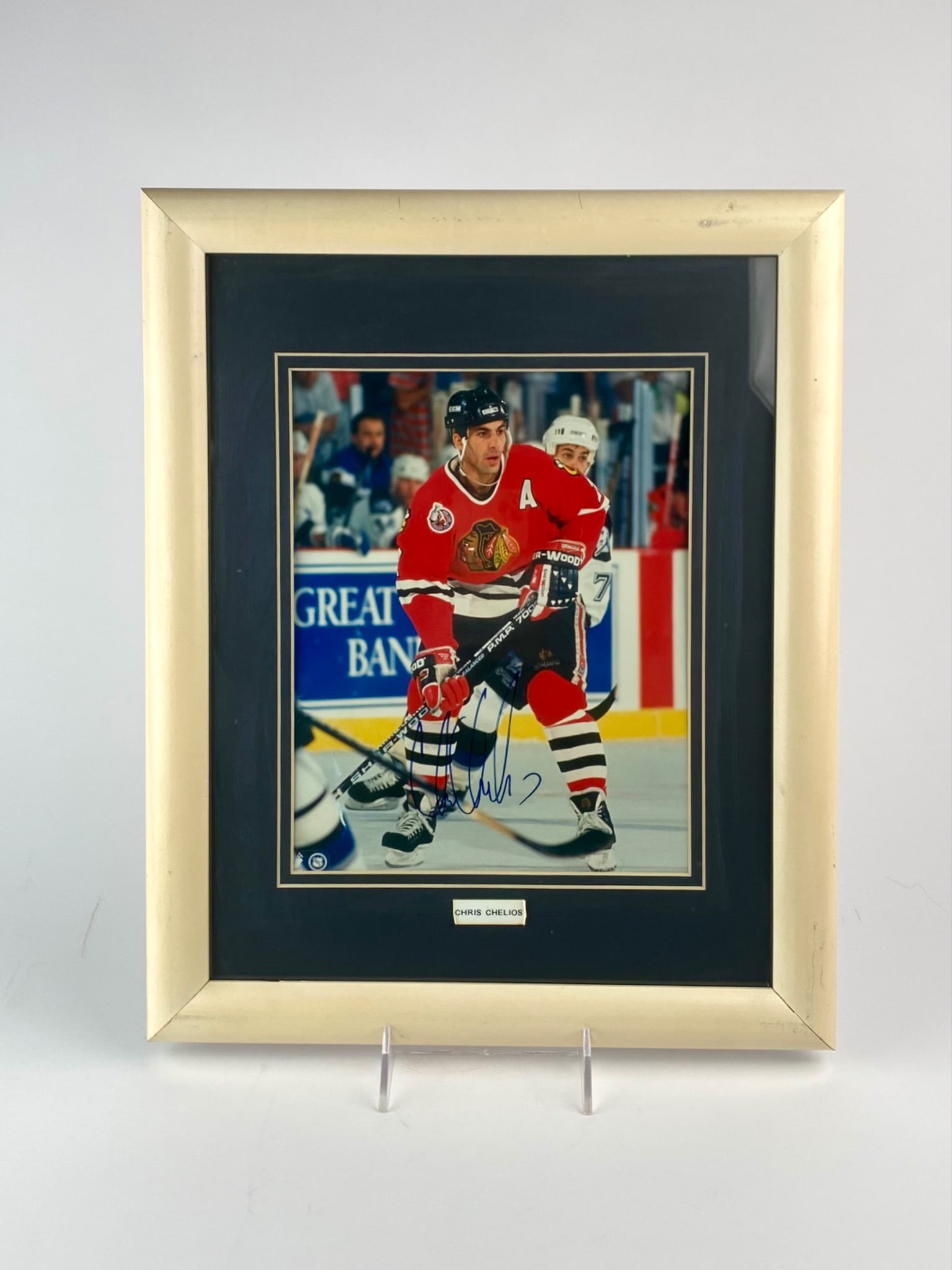 Framed Chris Chelios Autographed Chicago Blackhawks Photo: Framed color action photograph signed by Chris Chelios, Hall of Fame defenseman and former alternate captain of the Chicago Blackhawks. The photo captures Chelios in-gem wearing his iconic red Blackha