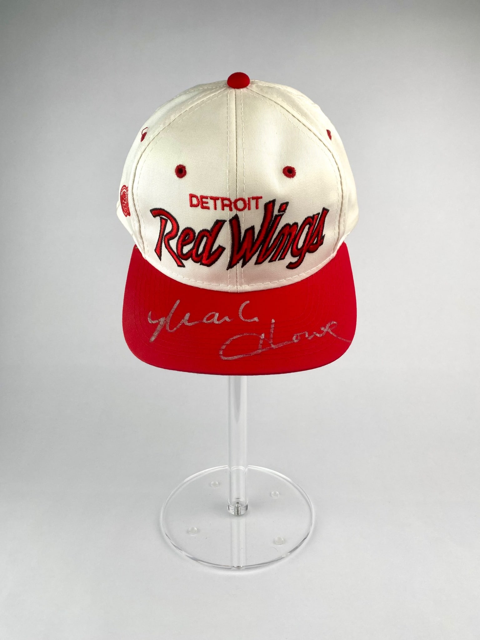Detroit Red Wings Baseball Cap Signed by Mark Howe: Vintage Detroit Red Wings snapback cap by The Twill, featuring red and white panel construction with embroidered team branding and NHL logo tag. The red brim is boldly signed in silver marker by Hocke