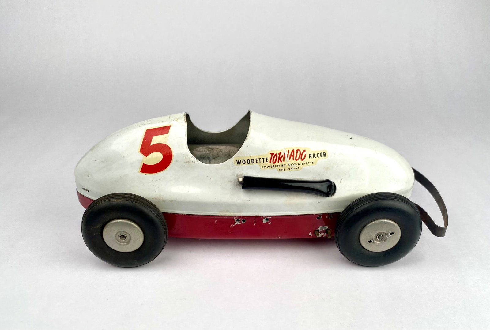 Woodette Toronado Racer, Winzeler Mfg., Metal Toy Car: Woodette Toronado Racer, manufactured by Winzeler Mfg. Co., Chicago, USA. Constructed of metal with white and red paint finish and black details. Features the number ‘5’ and the logo ‘Woodette T