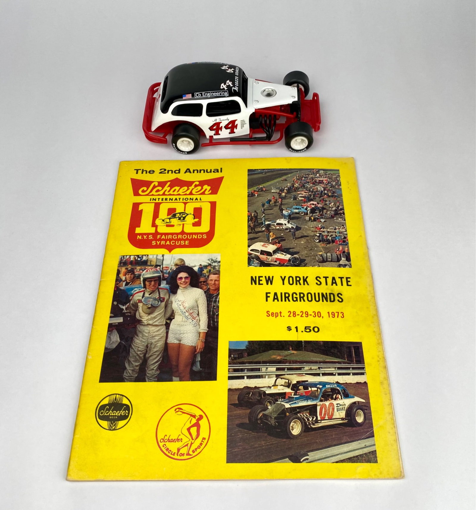 1973 Schafer 100 Program with Die-Cast Model Car #44: 1973 Schafer 100 New York State Fairgrounds program from the 2nd Annual event (Sept. 28-30, 1973), priced at $1.50. Includes historical content, race results, and advertisements. Accompanied by a #44 
