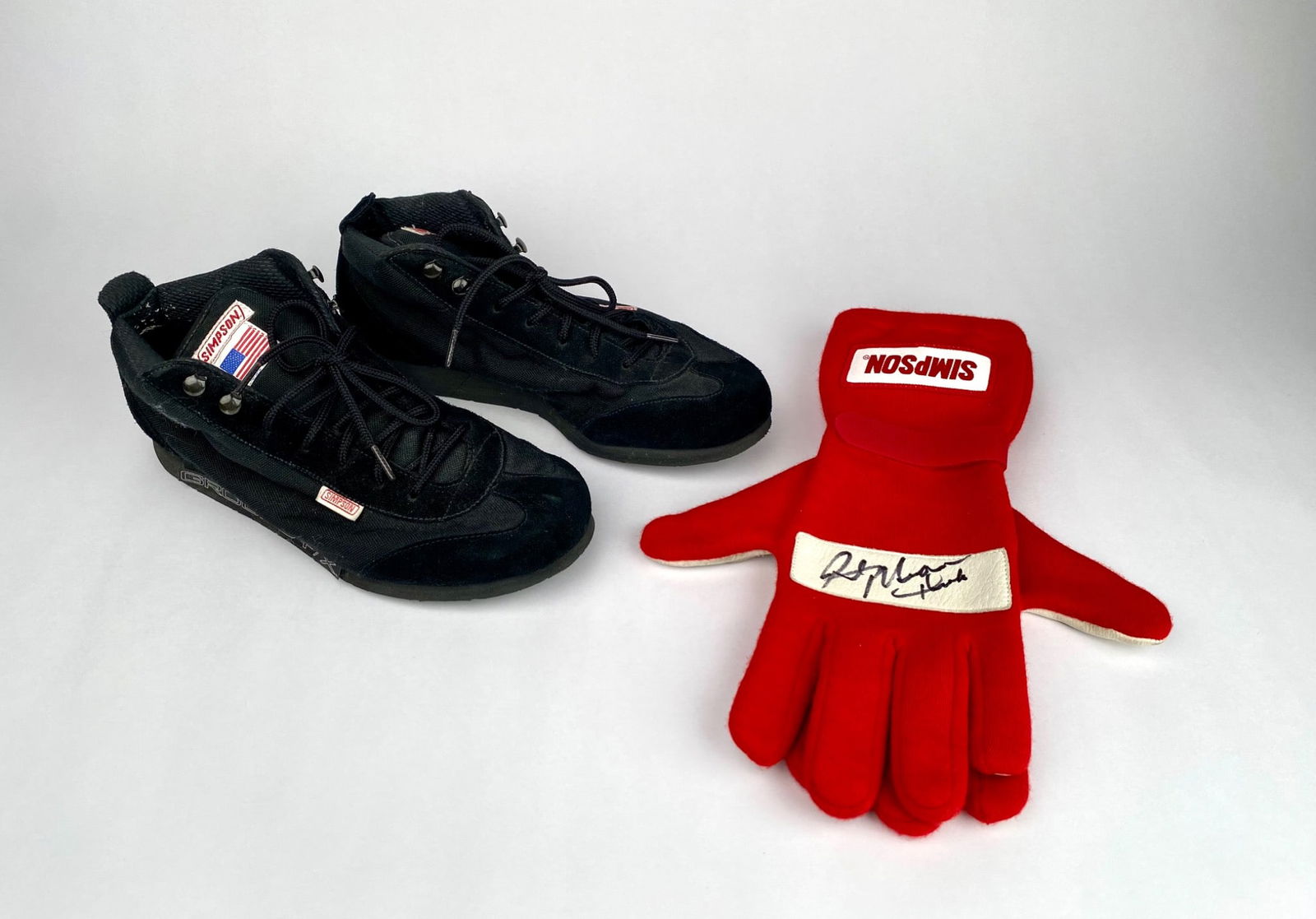 Simpson Racing Shoes and Autographed Gloves – Rick Mears: Simpson racing shoes in black, featuring ‘Ground FX’ on the sides and branding on the soles. Includes red Simpson gloves with padded palms, one glove autographed by Rick Mears. | Please see photos