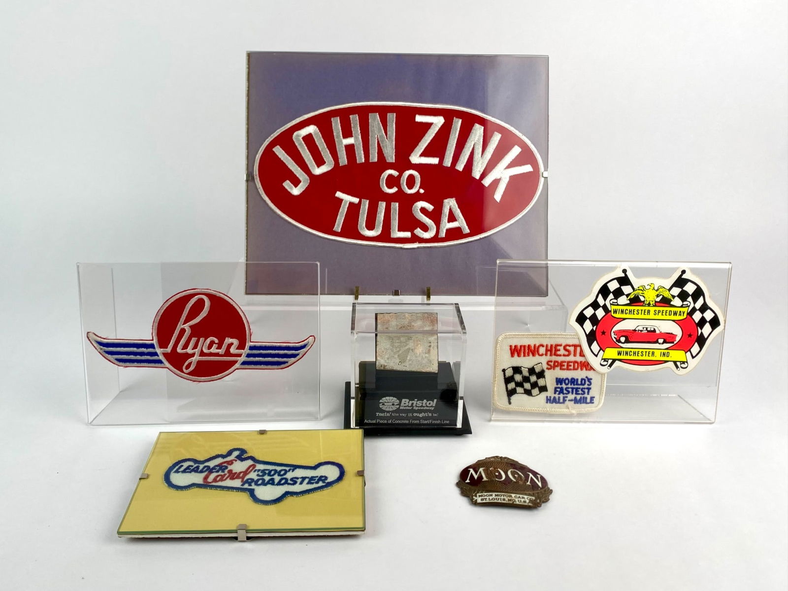 Collection of Vintage Racing Memorabilia – John Zink, Leader Card, Moon Motor Car & Bristol: Group lot featuring a selection of vintage racing memorabilia. Included is a large, embroidered John Zink Co. Tulsa patch, a Leader Card “500 Roadster” patch, and a pair of Winchester Speedway