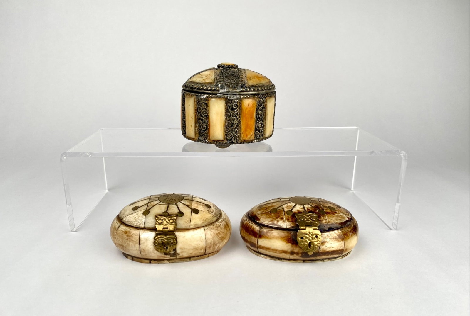 Three Bone and Metal Boxes with Inlay and Hinged Lids: Three boxes crafted in Morocco and India featuring a combination of bone and metal materials. Includes one round box adorned with intricate metal filigree and bone panels, and two oval boxes with deco