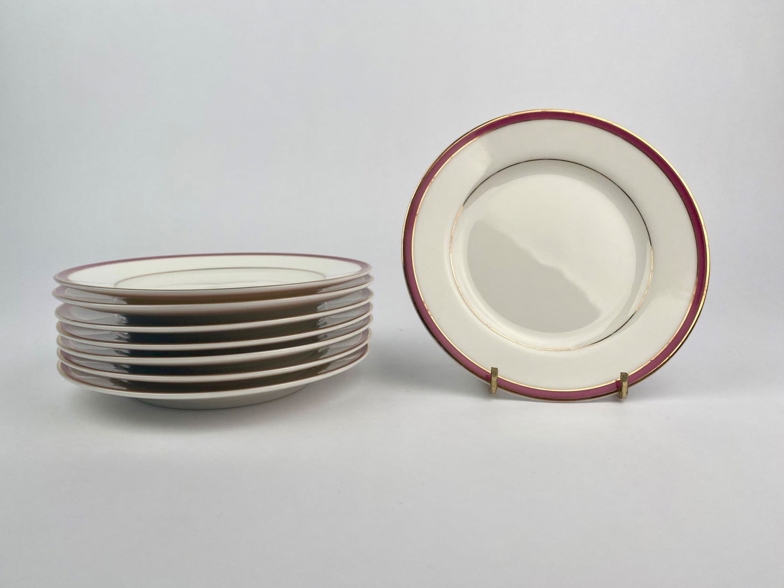 Set of 8 International Ultra Bone Japan Bread & Butter Plates: Set of eight bread and butter plates by International Ultra Bone, Japan. Each plate features a classic design with a reddish pink border and fine gold rim on a white porcelain background. The undersid