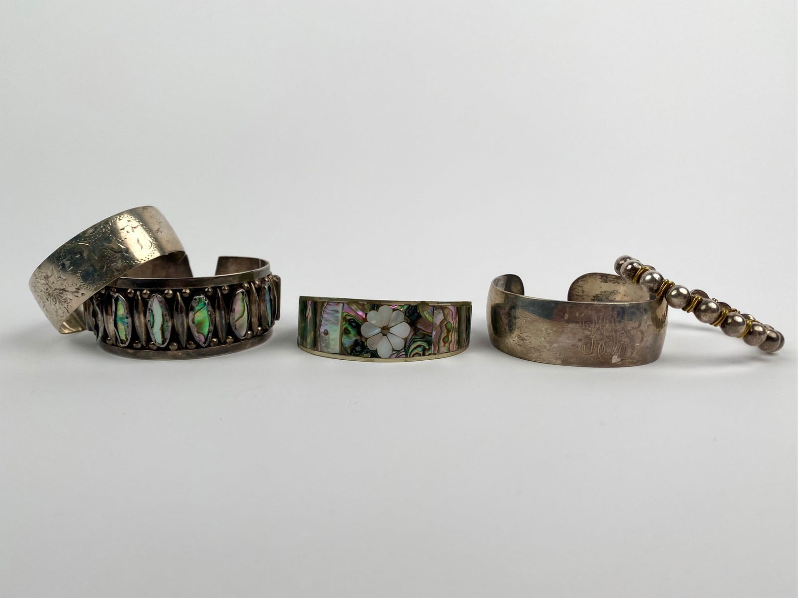 Set of Five Vintage Sterling & Alpaca Cuff Bracelets: Five vintage cuffs bracelets including four marked sterling with abalone inlay and engraved designs, and one unmarked silver-tone cuff. Light wear and tarnish are present to each cuff bracelet. Please