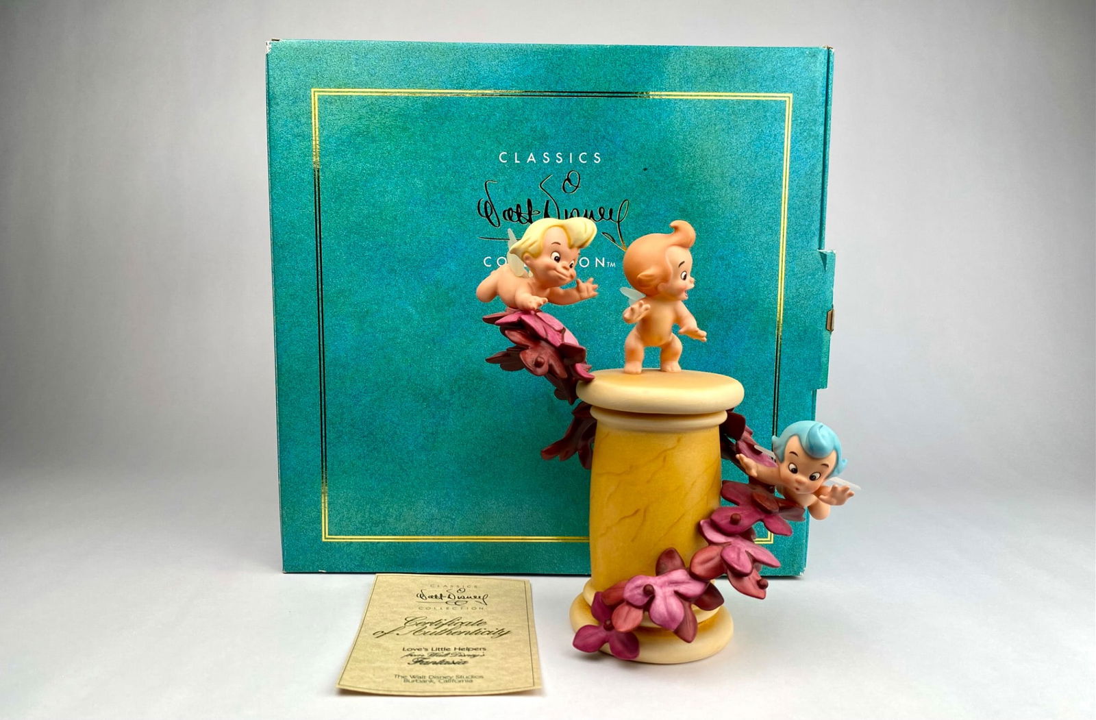 Walt Disney Classics Collection Fantasia Figurine ‘Love’s Little Helpers’ with COA & Box: Walt Disney Classics Collection figurine titled ‘Love’s Little Helpers’ from Fantasia. Features three cherubic characters with translucent wings climbing a spool of thread adorned with purple fl