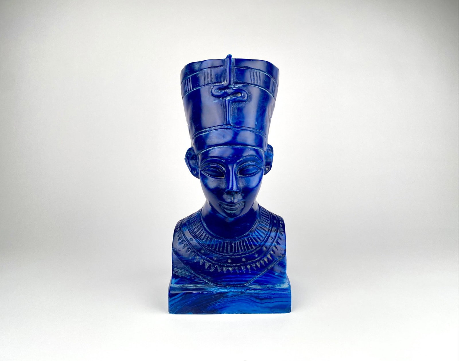 Blue Resin Bust of Nefertiti, Egyptian Revival Style: Blue resin bust of Queen Nefertiti featuring detailed facial features, headdress, and adornment. The sculptural depiction of Nefertiti displays an etched headdress and intricate detailing on her neckl
