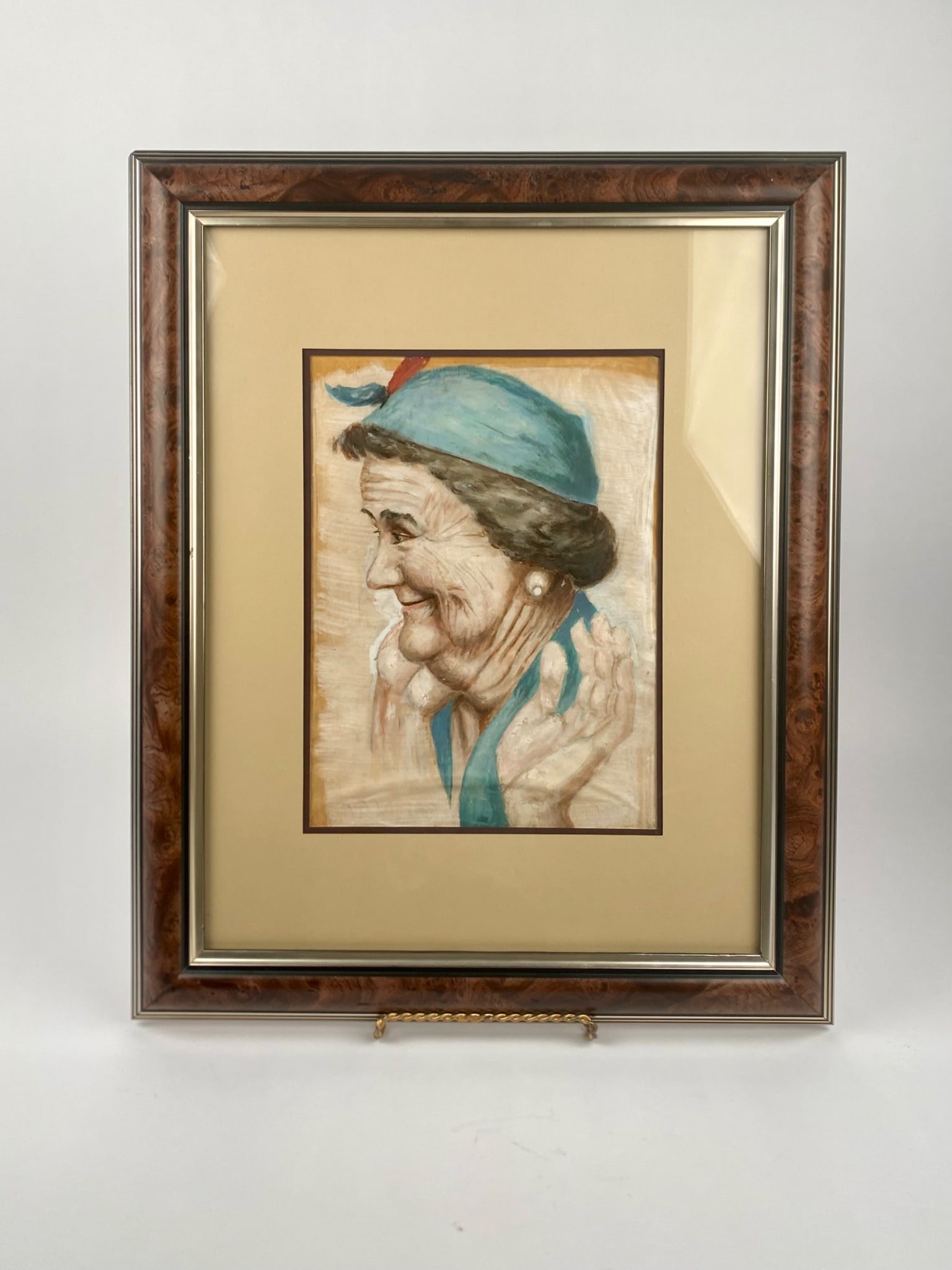 Framed Profile Portrait of an Elderly Woman: Framed and matted portrait of an elderly woman in profile, featuring detailed brushwork highlighting her blue headscarf and expressive hands. The woman is depicted smiling, with visible character line