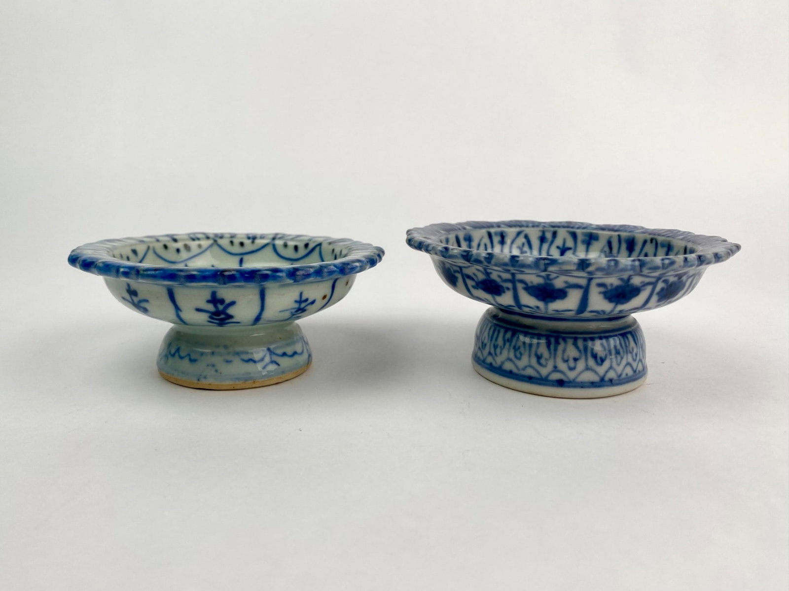 Pair of Hand Painted Blue and White Pedestal Dishes: Pair of vintage hand painted porcelain pedestal dishes, each featuring intricate cobalt blue underglaze floral and geometric designs on a white ground. The dishes are shallow with fluted rims and elev