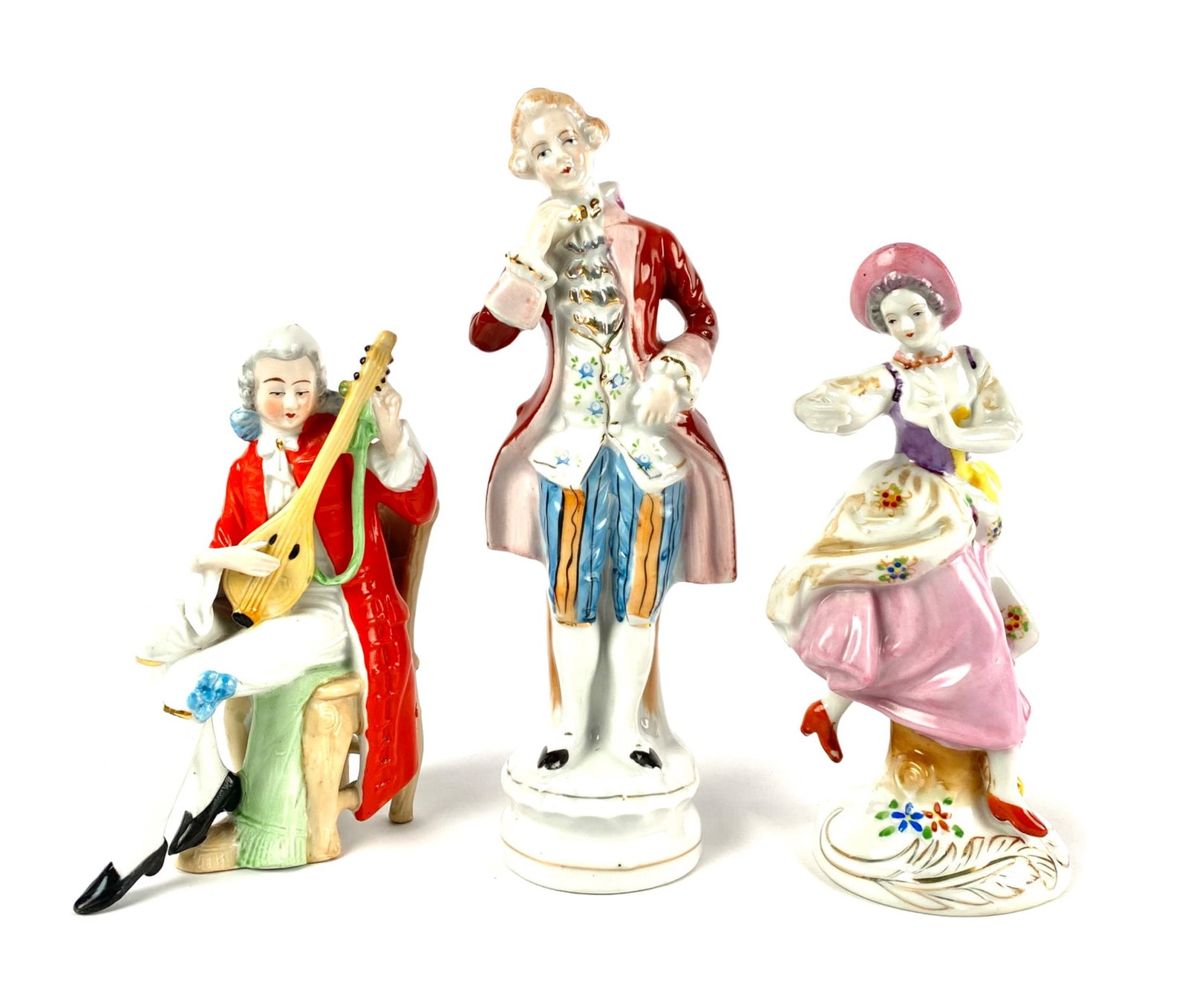Three Porcelain Figurines Depicting 18th-Century Attire: A collection of three hand-painted porcelain figurines depicting individuals dressed in 18th-century attire. The set includes a seated musician playing a string instrument, a male figure in formal att