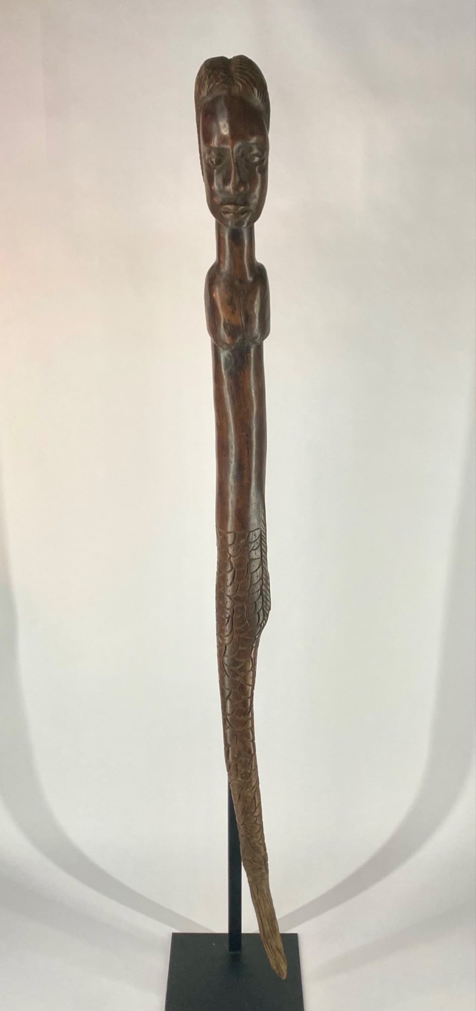 African Carved Wood Mermaid Figure with Figural Bust: Carved wood figural sculpture depicting a stylized female form transitioning into a fish tail. The surface shows a rich, dark patina consistent with age and handling. The carving exhibits hand-tooled