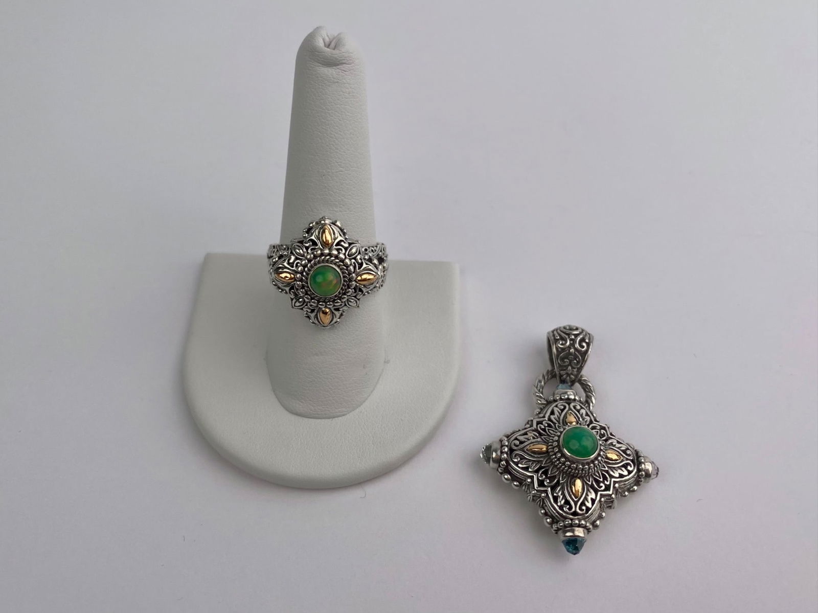 Sterling Silver Green Stone Ring & Pendant Set: Two-piece jewelry set consisting of a sterling silver ring and matching pendant, each featuring ornate openwork decoration with a central round green cabochon. The designs are accented with small appl
