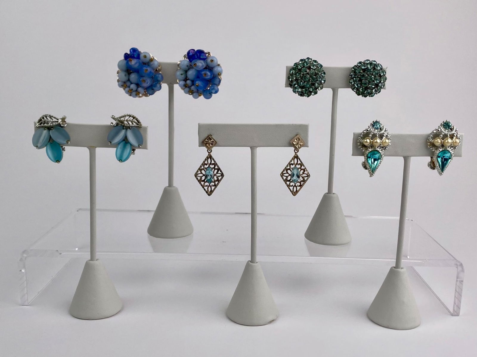 Set of Five Vintage Silver-Tone & Light Blue Stone Earrings: Group of five pairs of vintage earrings featuring silver-tone settings and light blue stones across several designs. Set includes a blue beaded cluster clip-on pair with gold-tone filigree backs marke