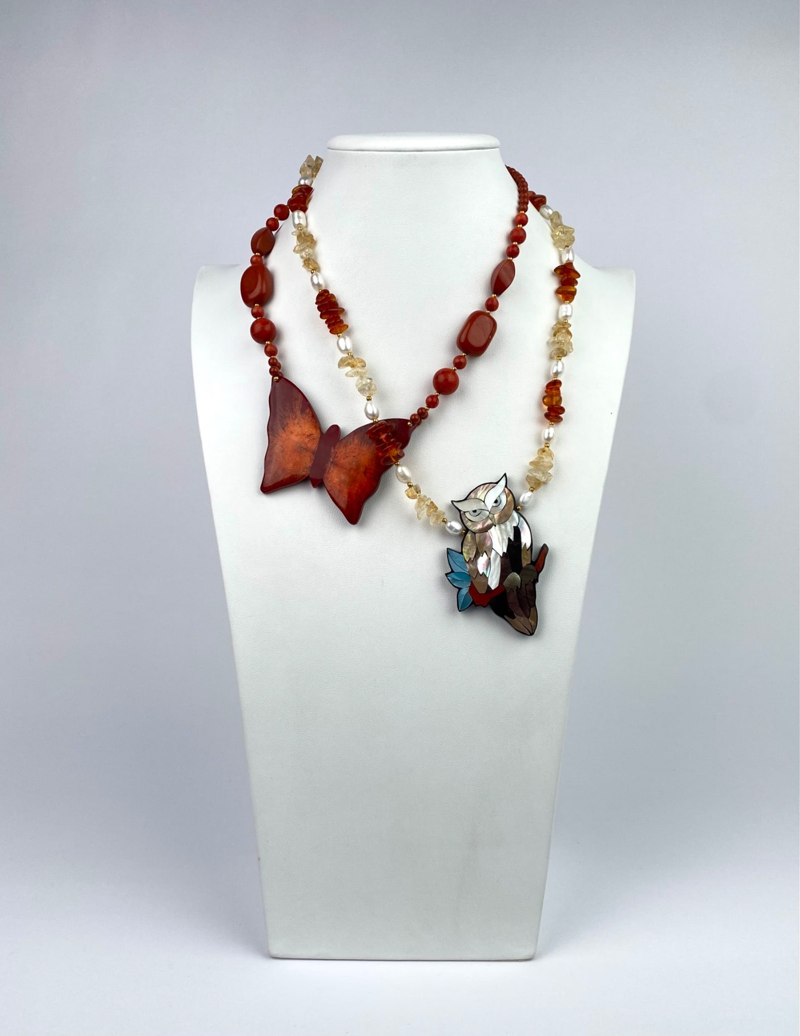 Lee Sands Necklaces Featuring Butterfly & Owl Motif: Pair of Lee Sands necklaces. The first necklace features a large butterfly pendant composed of reddish-brown material, paired with stone beads in coordinating hues. The second necklace showcases an ow