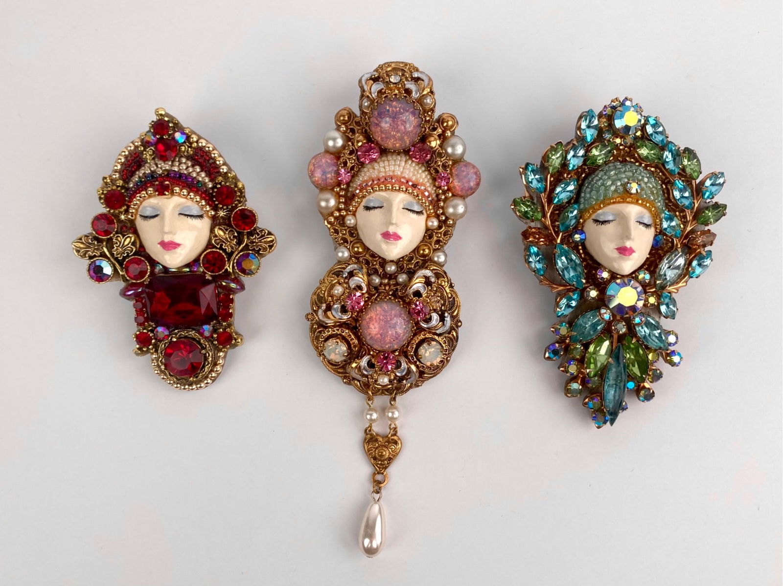 Set of Three J. Solomon Figural Rhinestone Brooches: Group of three oversized figural brooches by J. Solomon, each depicting a stylized female face framed by elaborate headdresses set with multicolored rhinestones, faux pearls, and beaded accents. Desig