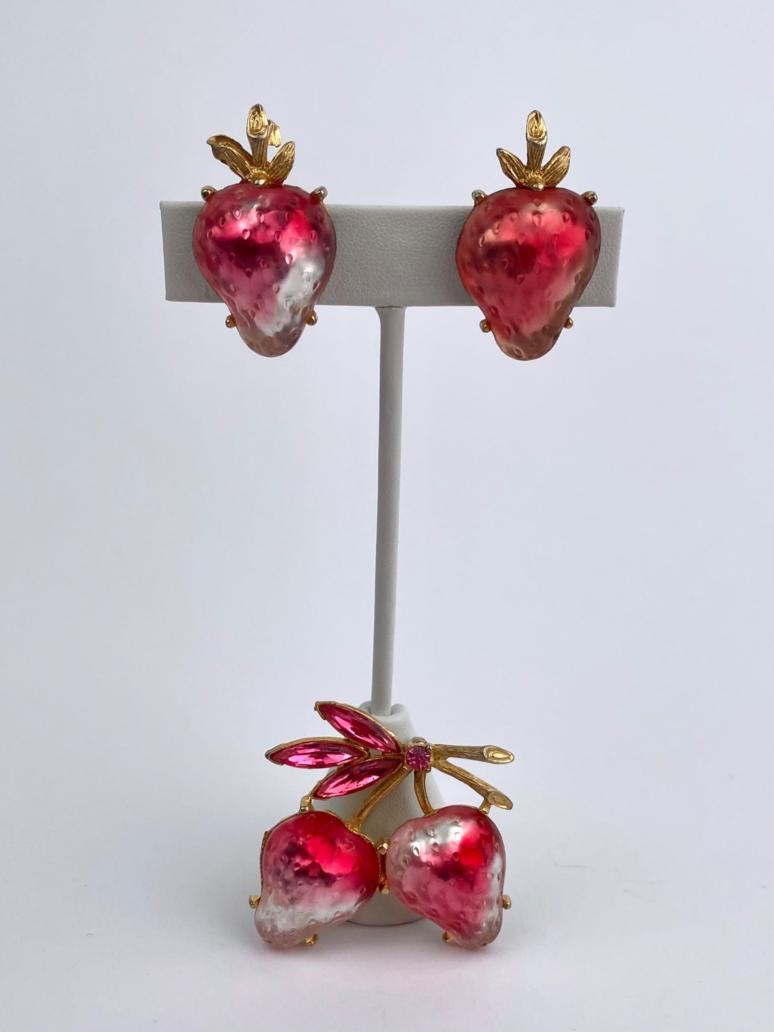 Vintage Strawberry Brooch & Clip-On Earrings Set: Vintage coordinating brooch and clip-on earring set designed as stylized strawberries, featuring vibrant red-to-pink molded bodies with textured seed detailing. The berries are topped with gold-tone l