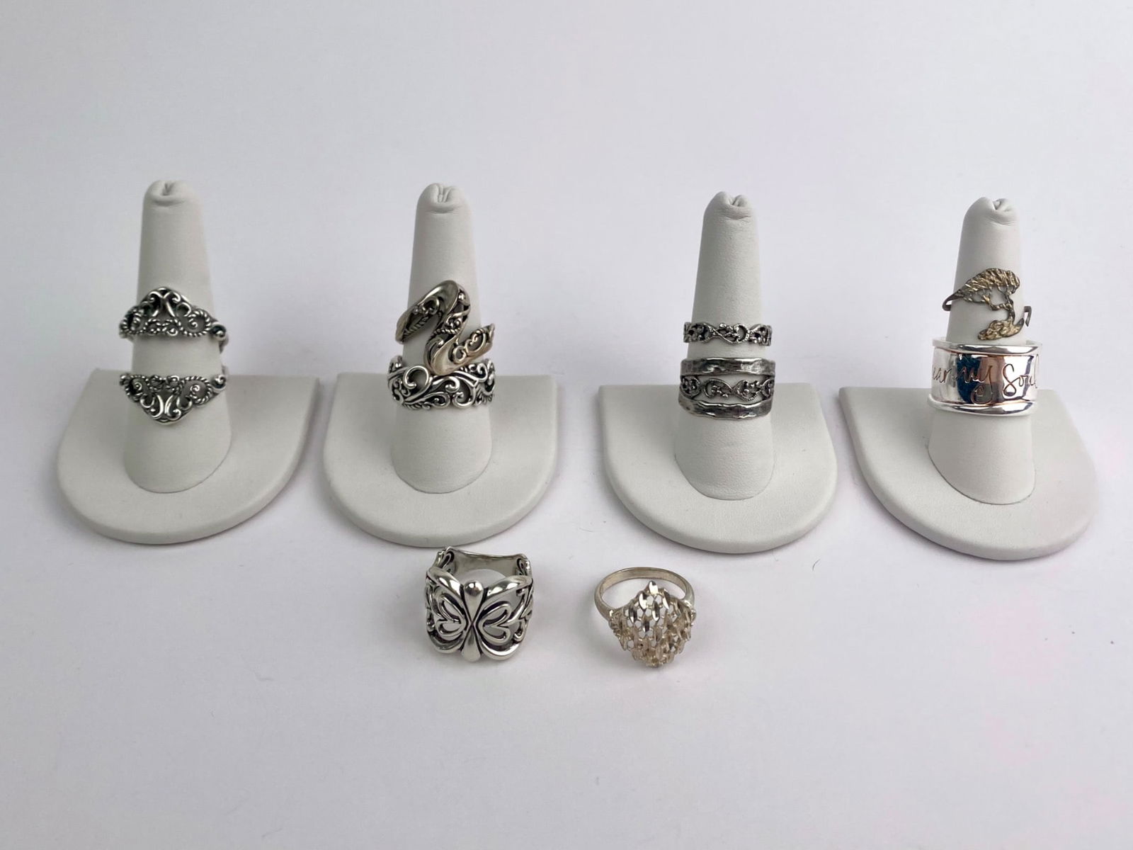 Group of Eight Sterling Silver Rings: Group of eight rings, crafted in sterling silver, featuring a variety of vintage and modern designs. The group includes wide band rings, scrolling foliate and floral motifs, rope and crossover forms,