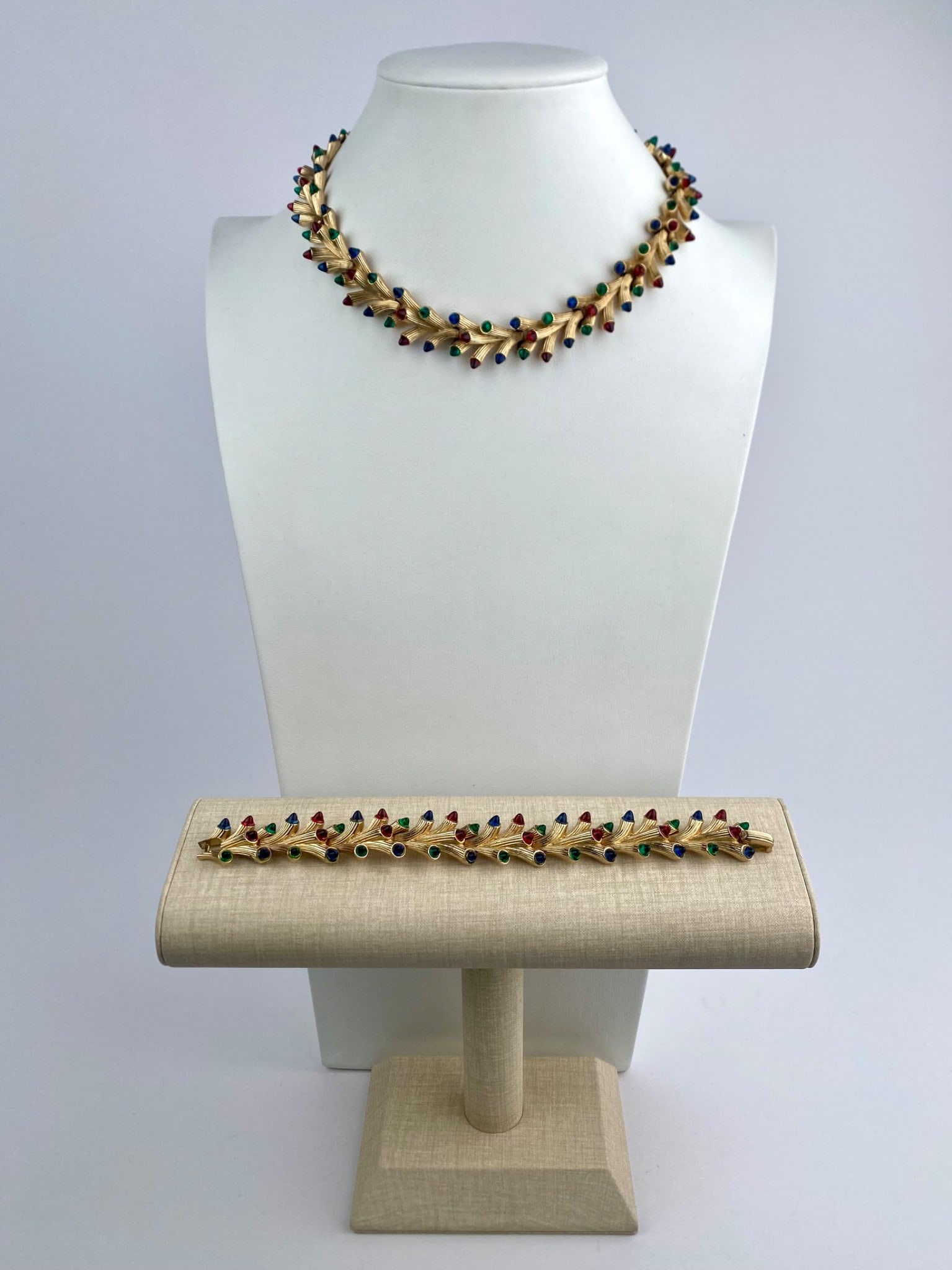 Vintage Trifari Gold-Tone Multicolor Cabochon Necklace and Bracelet Set: Vintage costume jewelry set by Trifari, consisting of a matching necklace and bracelet, executed in gold-tone metal. Both pieces feature a repeating link design, each set with multicolor cabochon acce