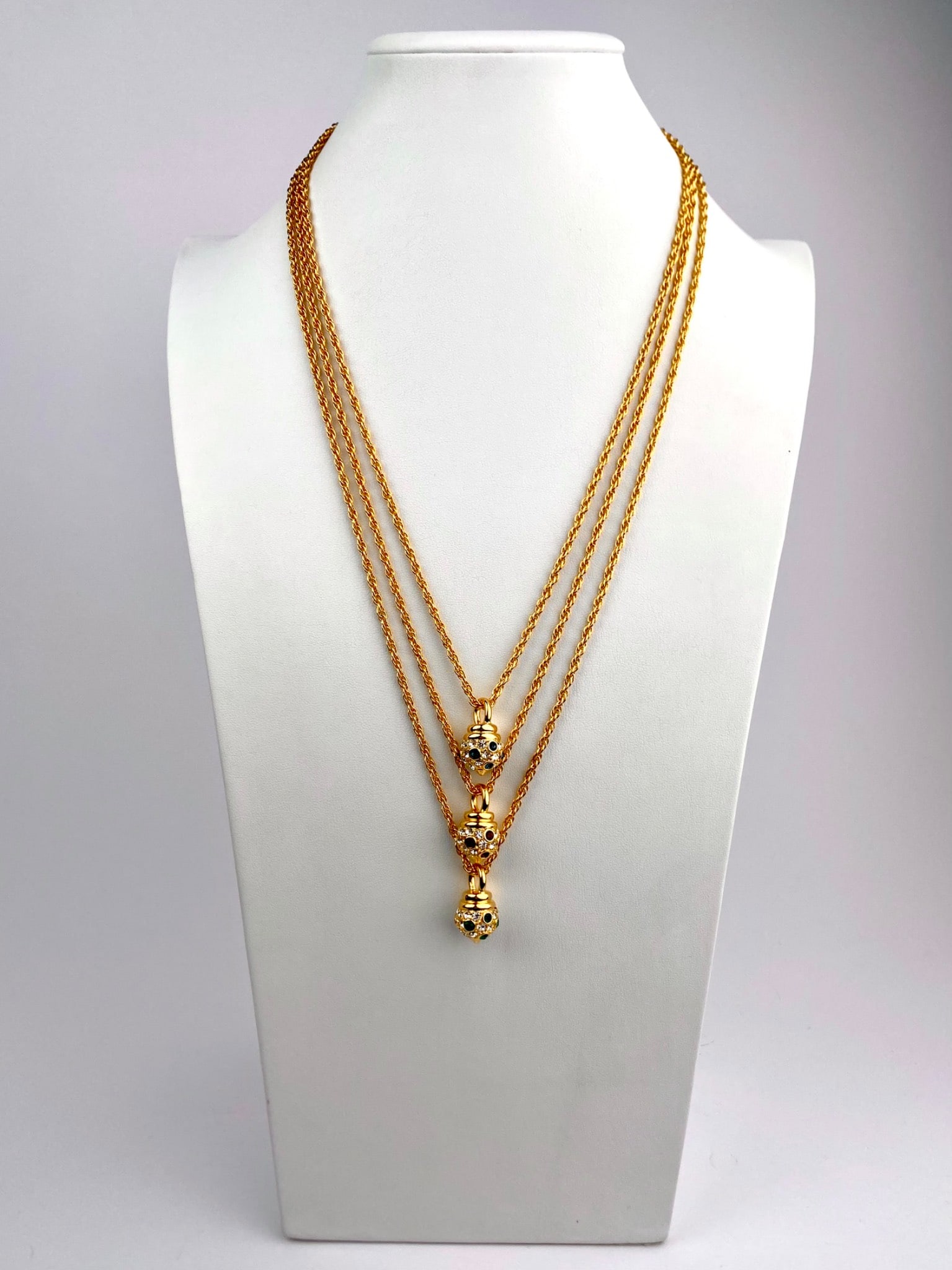 Nolan Miller Signed Trio of Gold-Tone Pendant Necklaces with Crystal Accents: Group of three signed Nolan Miller gold-tone necklaces, each featuring a rope-style chain and a coordinating pendant set with clear and colored crystal accents. The pendants are dome-form with pave-st