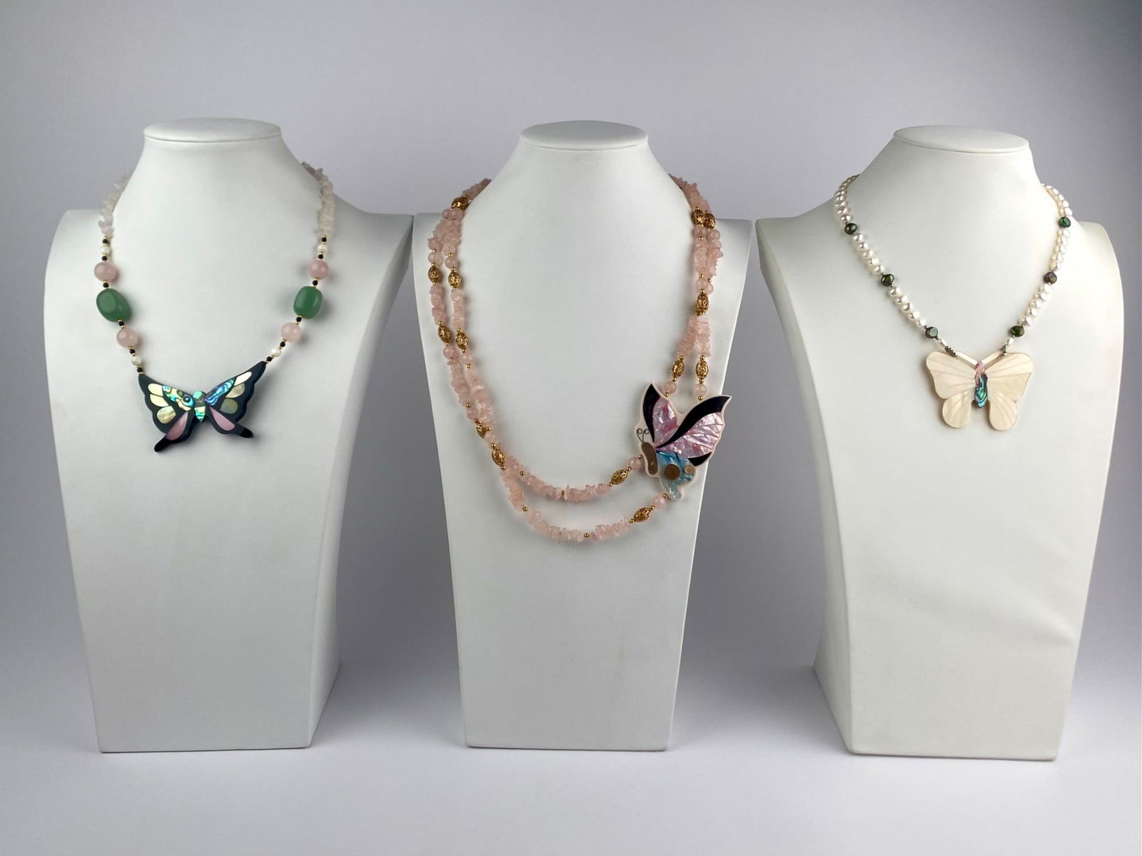Group of Three Lee Sands Butterfly Pendant Necklaces: Group includes three beaded necklaces by Lee Sands, each centered with a carved butterfly pendant. The necklaces feature mixed materials including rose quartz chips and beads, freshwater pearls, green